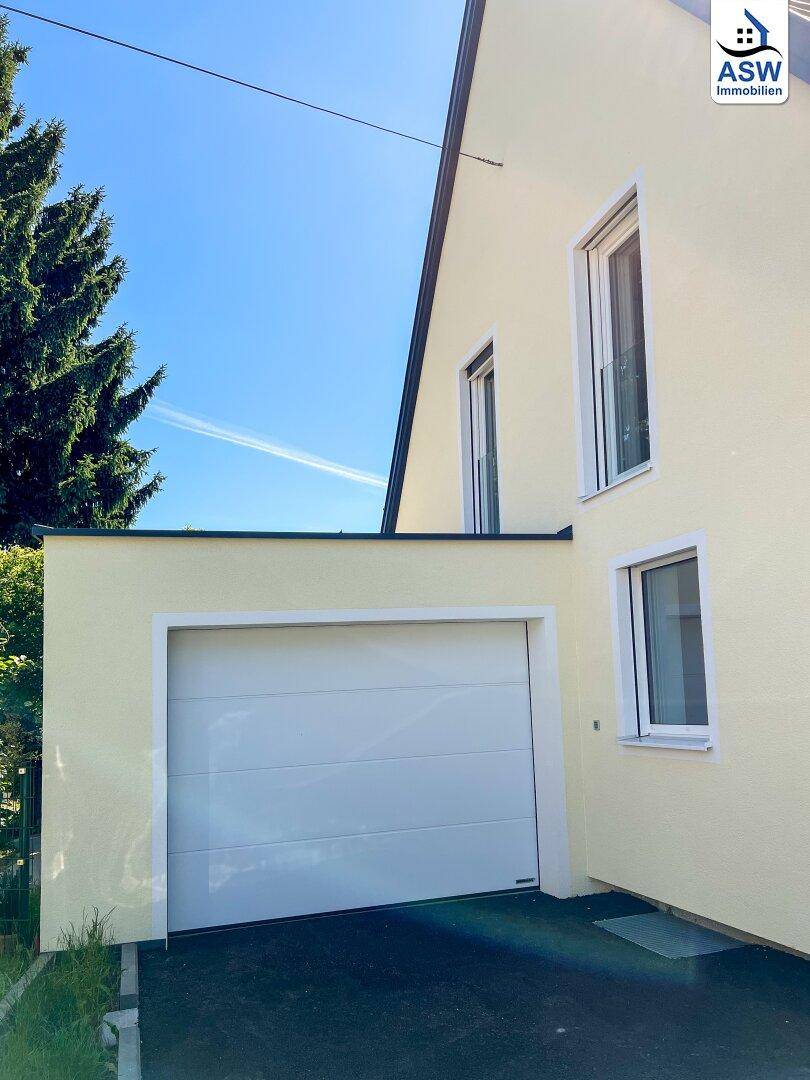 Moderne Einzelgarage mit weißem Sektionaltor, direkt am Haus gelegen.