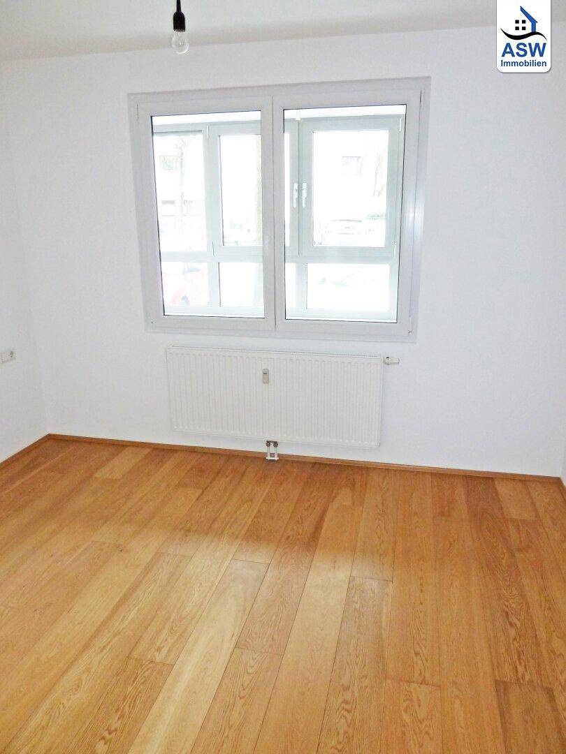 Helles Schlafzimmer mit Holzfußboden und großem Fenster, bietet eine ruhige Atmosphäre.