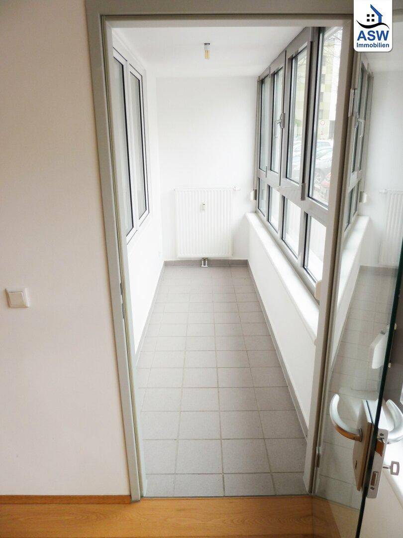 Verglaste Loggia mit Fliesenboden und Heizkörper, bietet zusätzlichen geschützten Wohnraum.