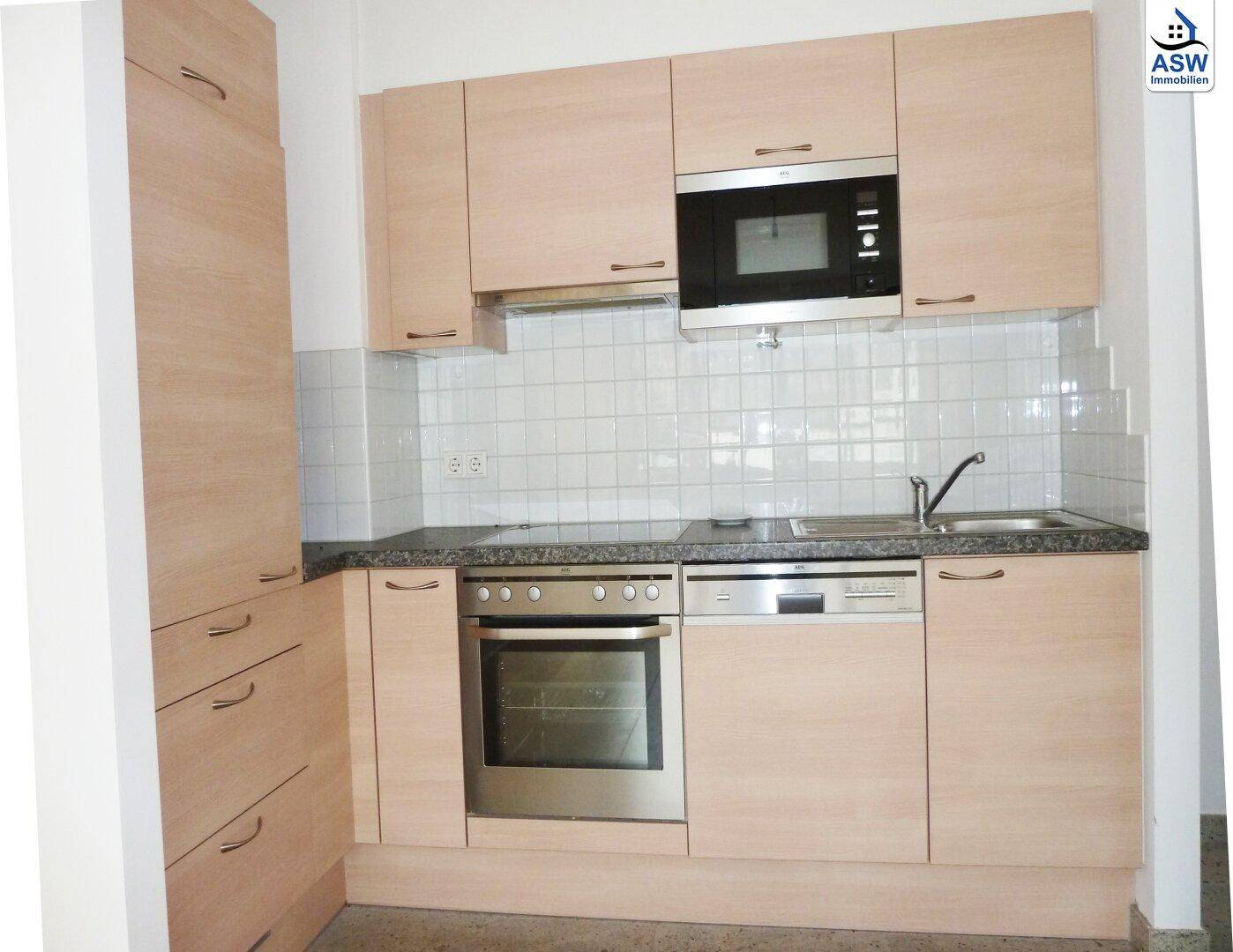 Funktionale Einbauküche mit hellen Holzfronten, Granitarbeitsplatte und integrierten Geräten.