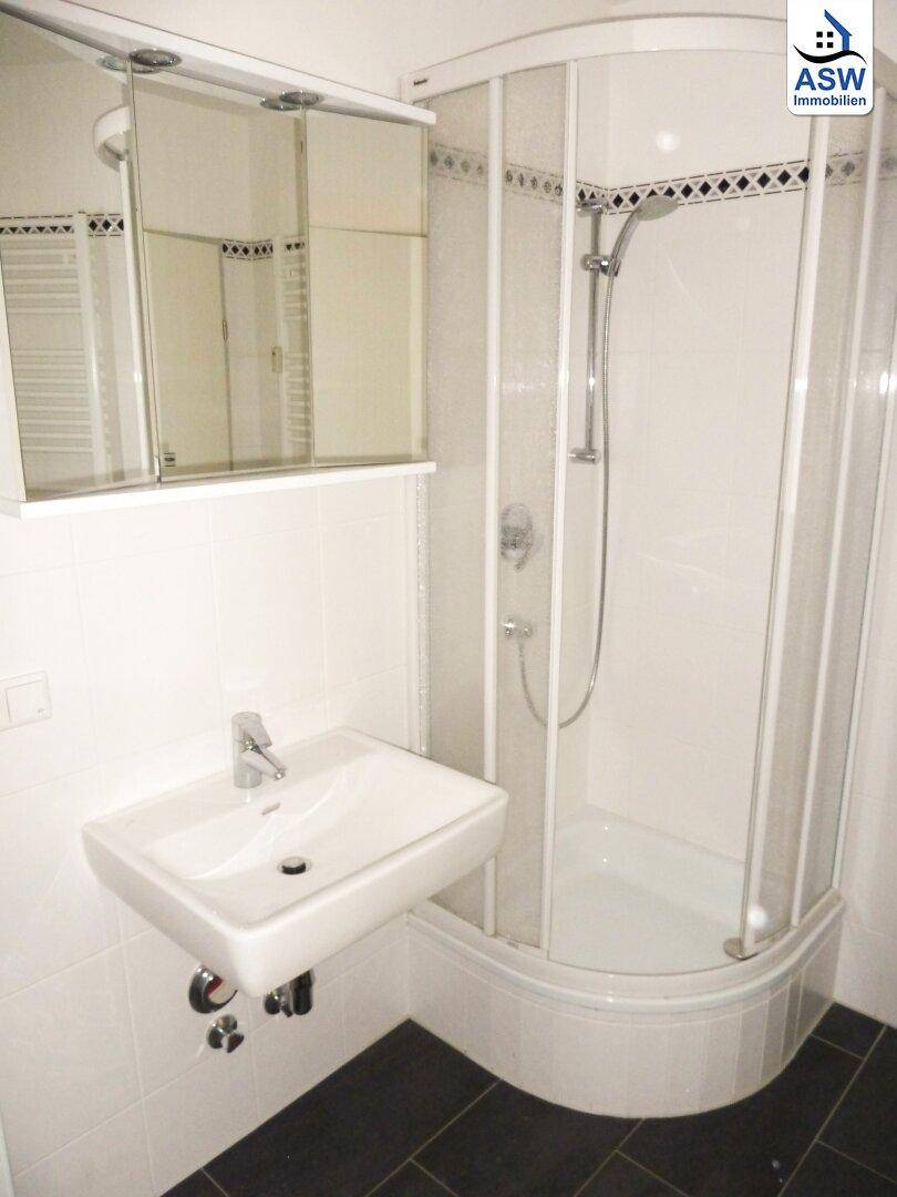 Modernes Badezimmer mit Duschkabine, Waschbecken und Spiegelschrank, in gutem Zustand.
