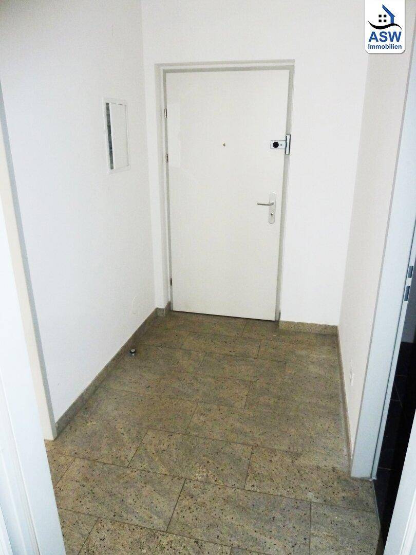 Eingangsbereich mit Fliesenboden und weißer Wohnungstür, bietet einen praktischen Empfang.