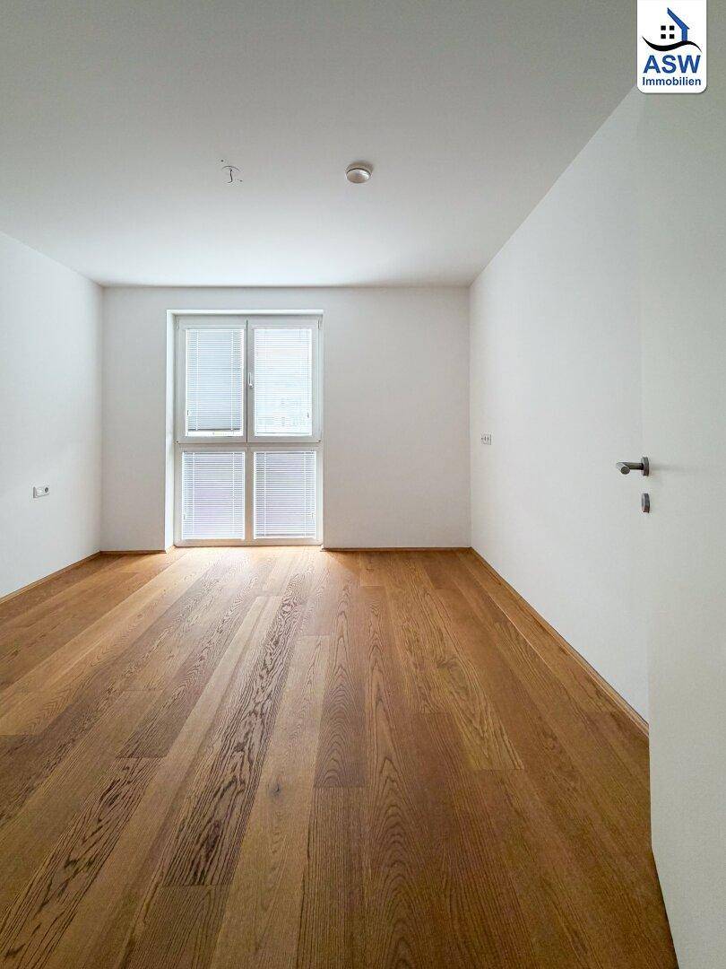 Geräumiges Zimmer mit Parkettboden und Fenster, das viel natürliches Licht spendet.
