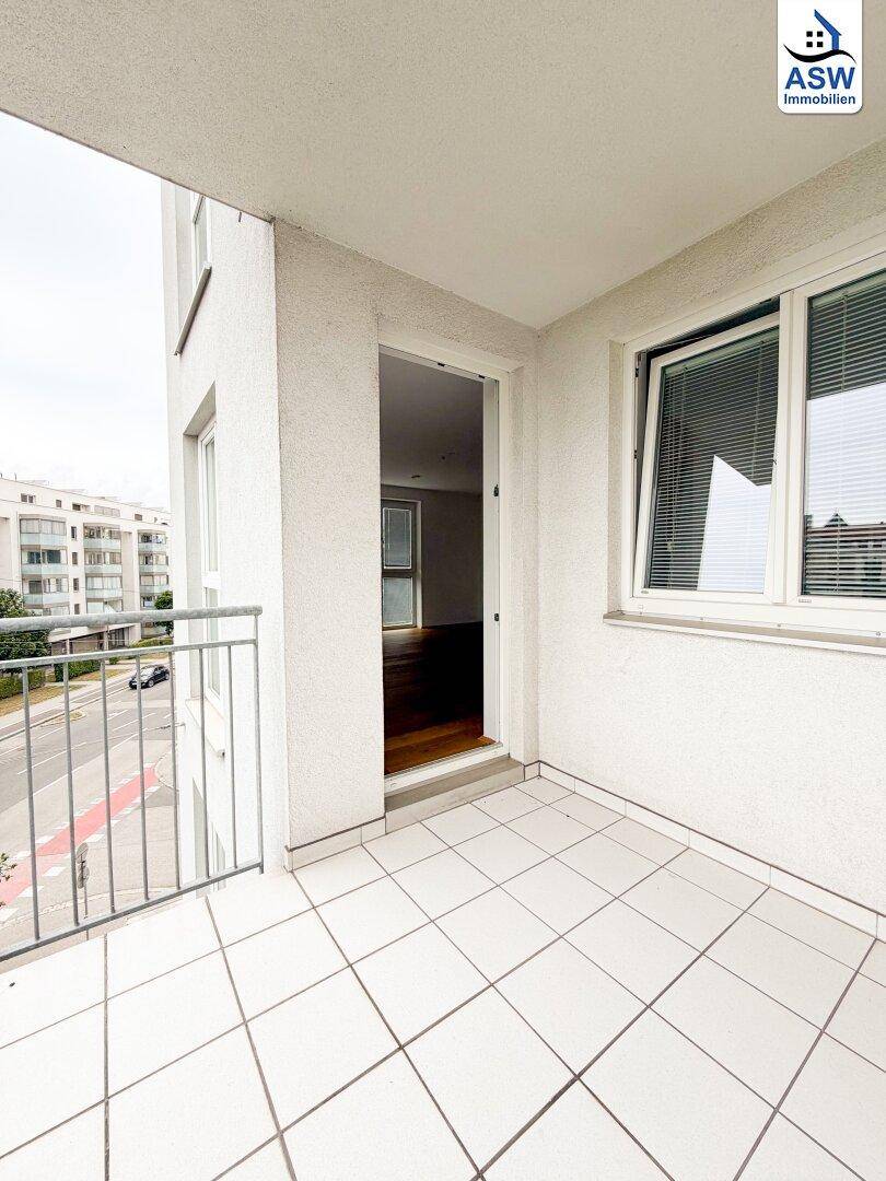 Heller Balkon mit Fliesenboden und Zugang zum Innenbereich der Wohnung.