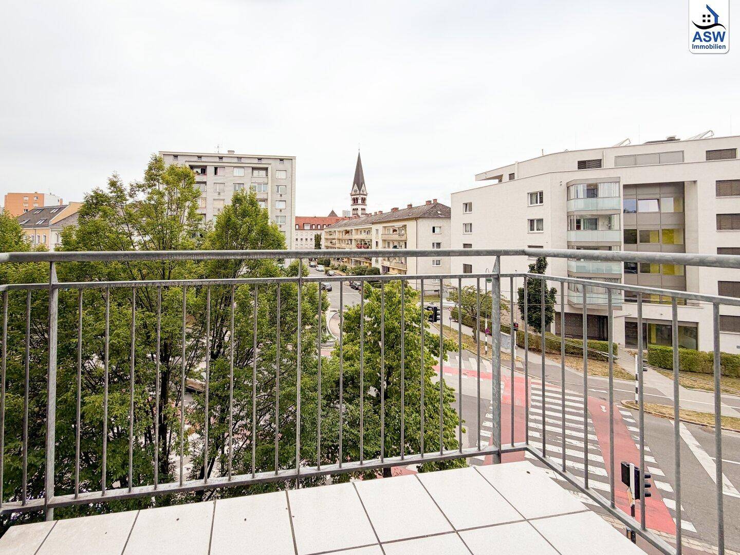 Balkon mit Blick auf die städtische Umgebung und grüne Bäume.