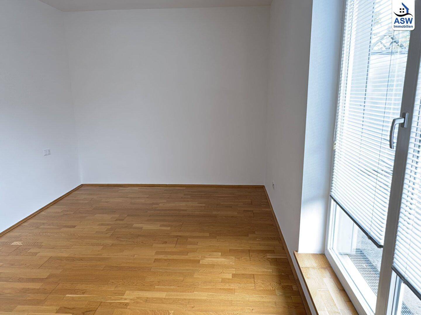 Geräumiges Schlafzimmer mit Parkettboden und großem Fenster, das viel Tageslicht hereinlässt.