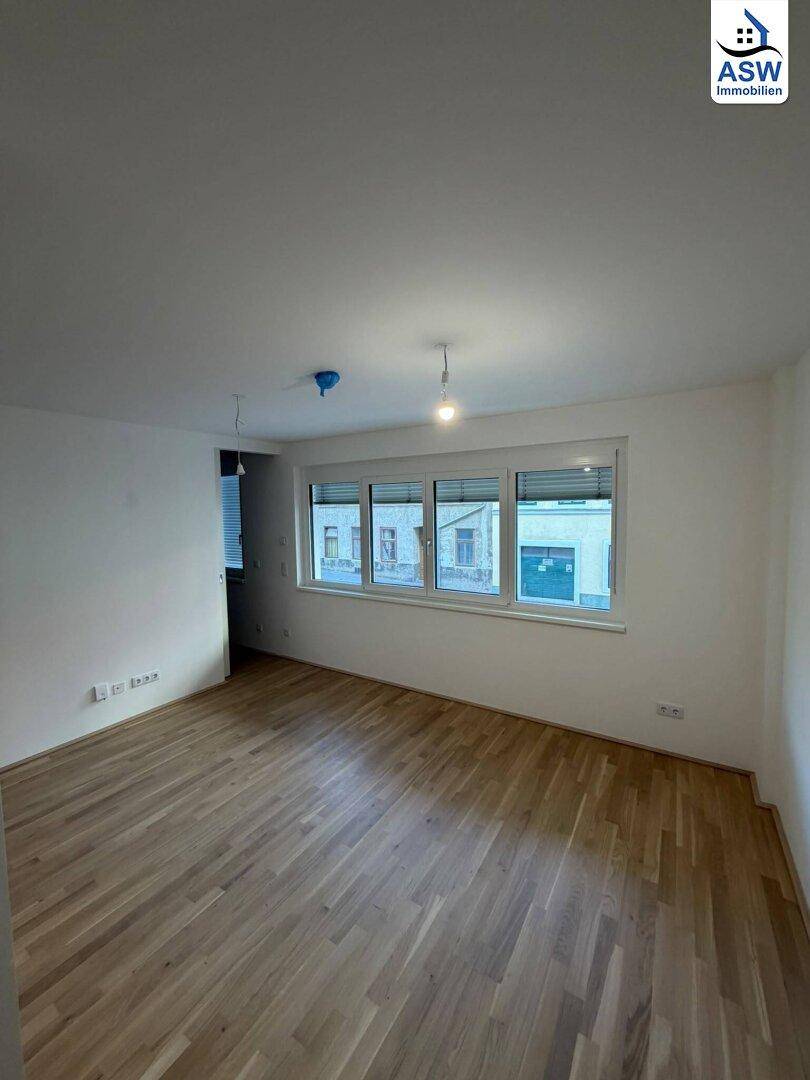 Geräumiger, heller Raum mit Parkettboden und großen Fenstern, ideal als Wohn- oder Schlafzimmer.