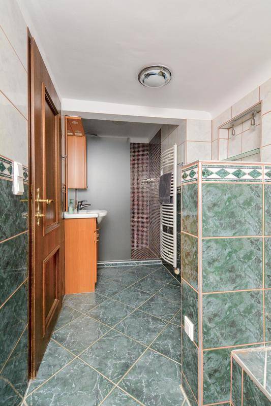 Badezimmer mit grünen Marmorfliesen, Einzelwaschbecken und Duschkabine.