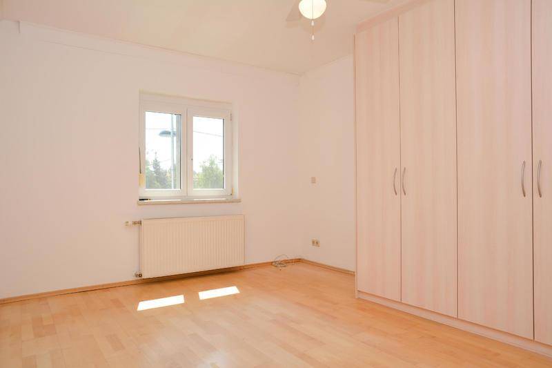 Helles Schlafzimmer mit hellem Holzboden und großem Einbauschrank.