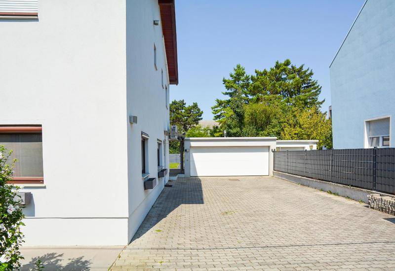 Geräumige Auffahrt mit Pflastersteinen und einer separaten Garage im Hintergrund.