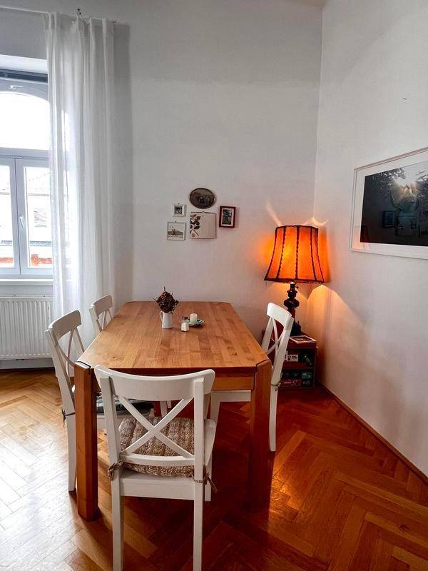 Heller Essbereich mit Holztisch, weißen Stühlen und dekorativer Lampe auf Fischgrätparkett.