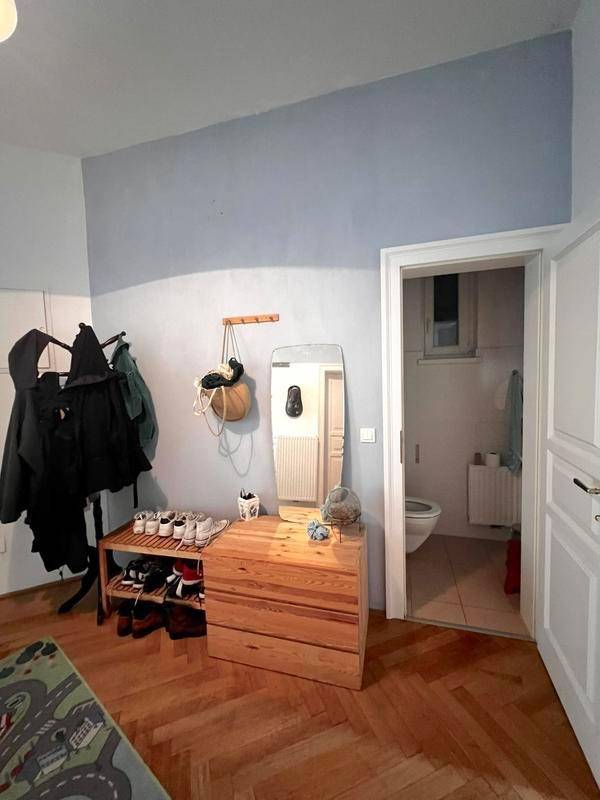 Zimmer mit Kommode, Spiegel und Zugang zu einem separaten WC, gestaltet mit blauen und weißen Wänden.