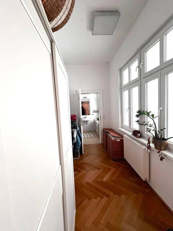Heller Flur mit großem Fenster, Einbauschrank und klassischem Fischgrätparkettboden.