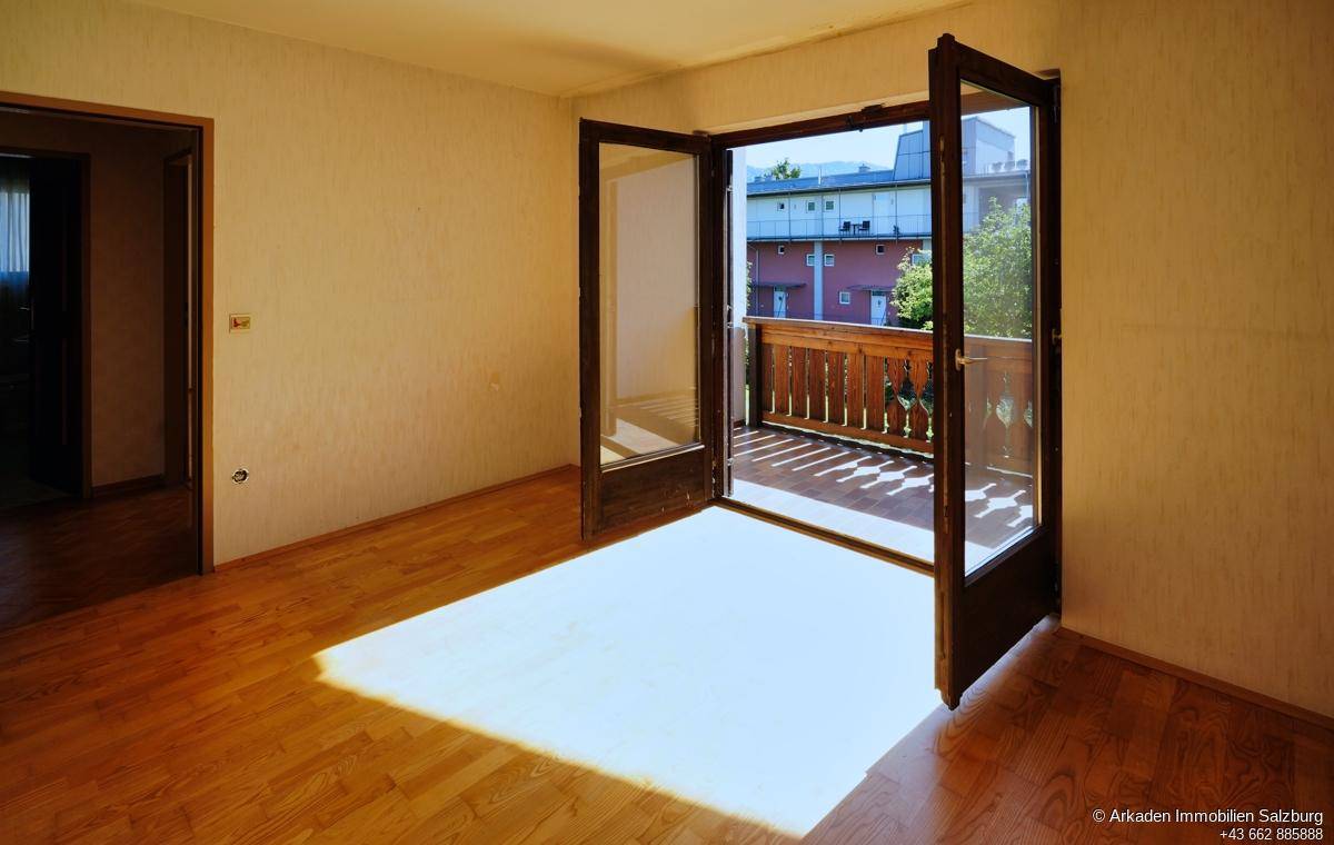 Lichtdurchfluteter Raum mit Holzfußboden und direktem Zugang zum sonnigen Balkon.