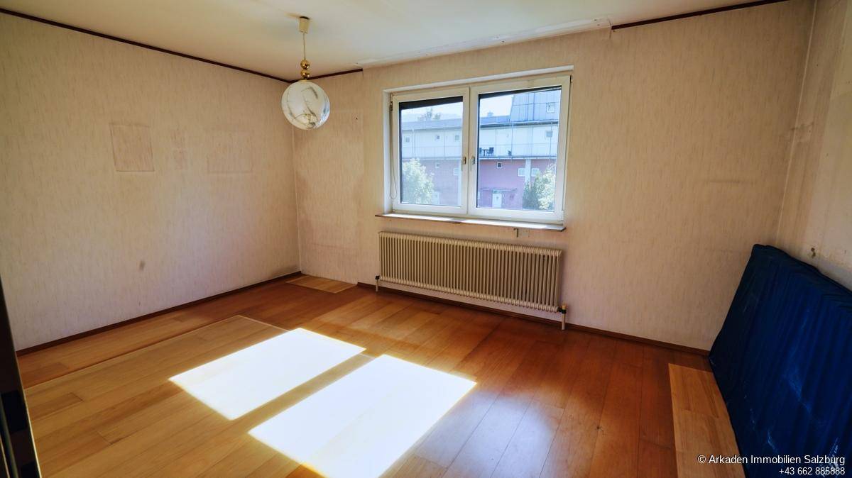 Helles Schlafzimmer mit Holzfußboden, großem Fenster und Blick auf die Umgebung.