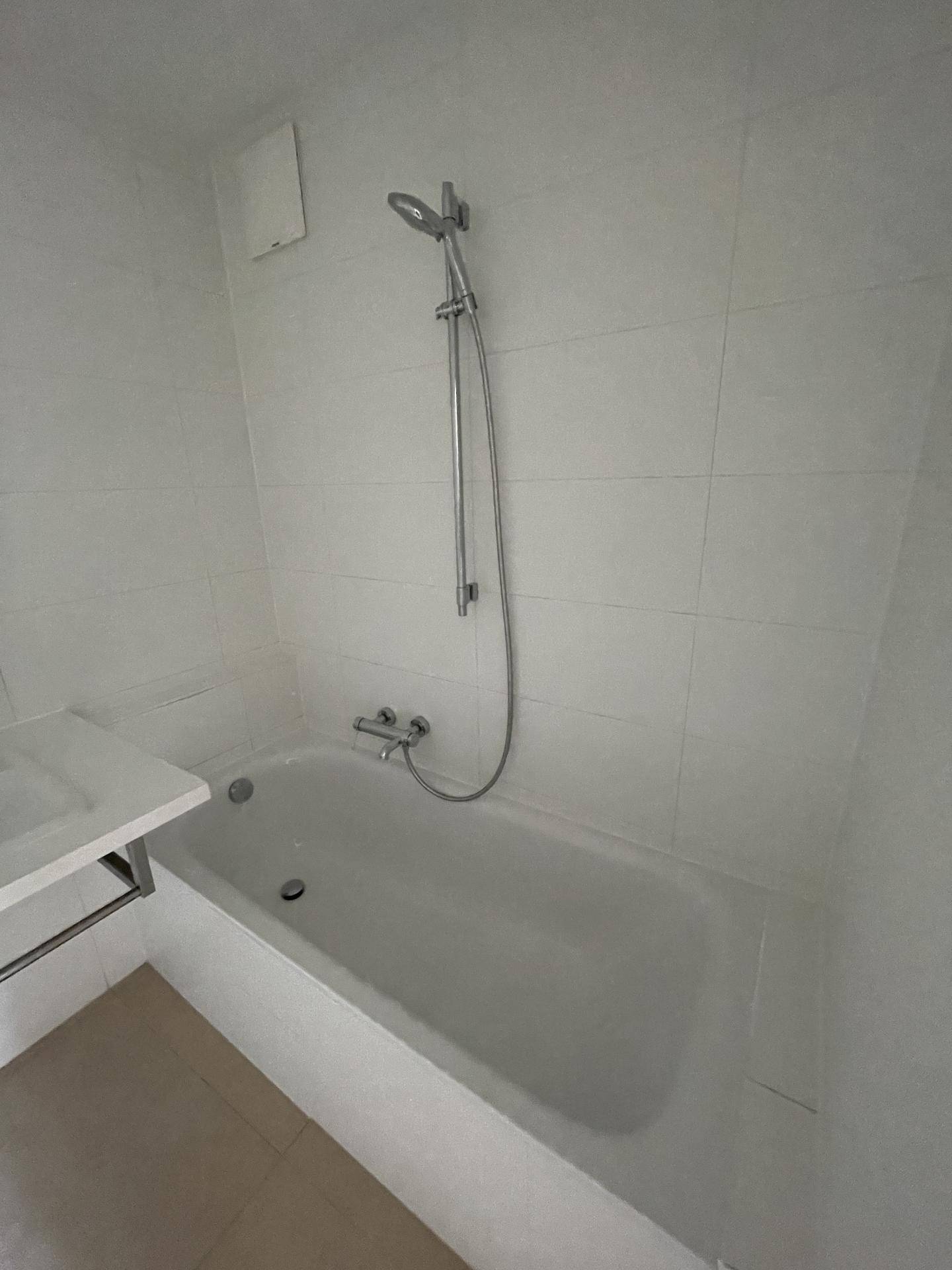 Modernes Badezimmer mit weißen Fliesen, einer Badewanne und integrierter Duschfunktion für Komfort.
