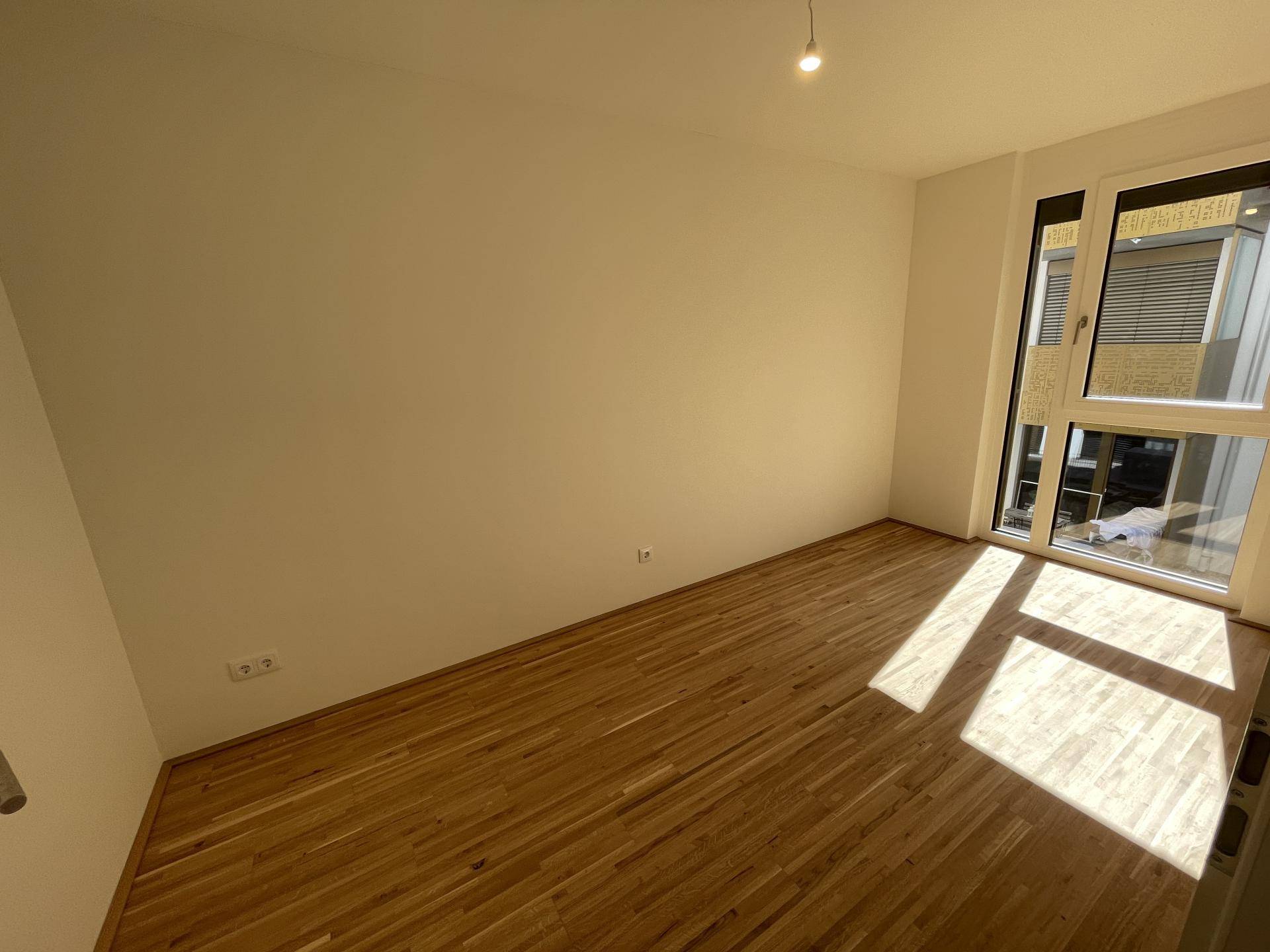 Helles Zimmer mit Parkettboden und bodentiefen Fenstern, ideal als Schlaf- oder Arbeitszimmer.