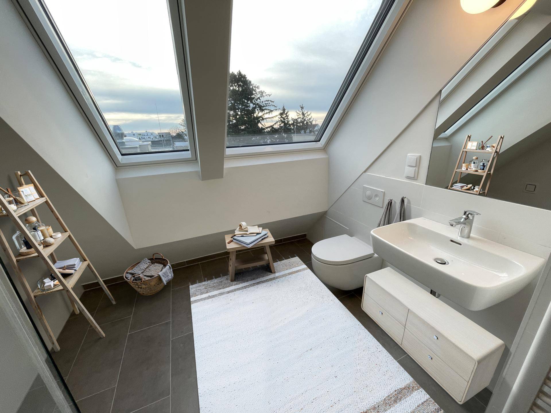 Modernes Badezimmer mit Waschtisch, WC und großen Dachfenstern mit Ausblick.