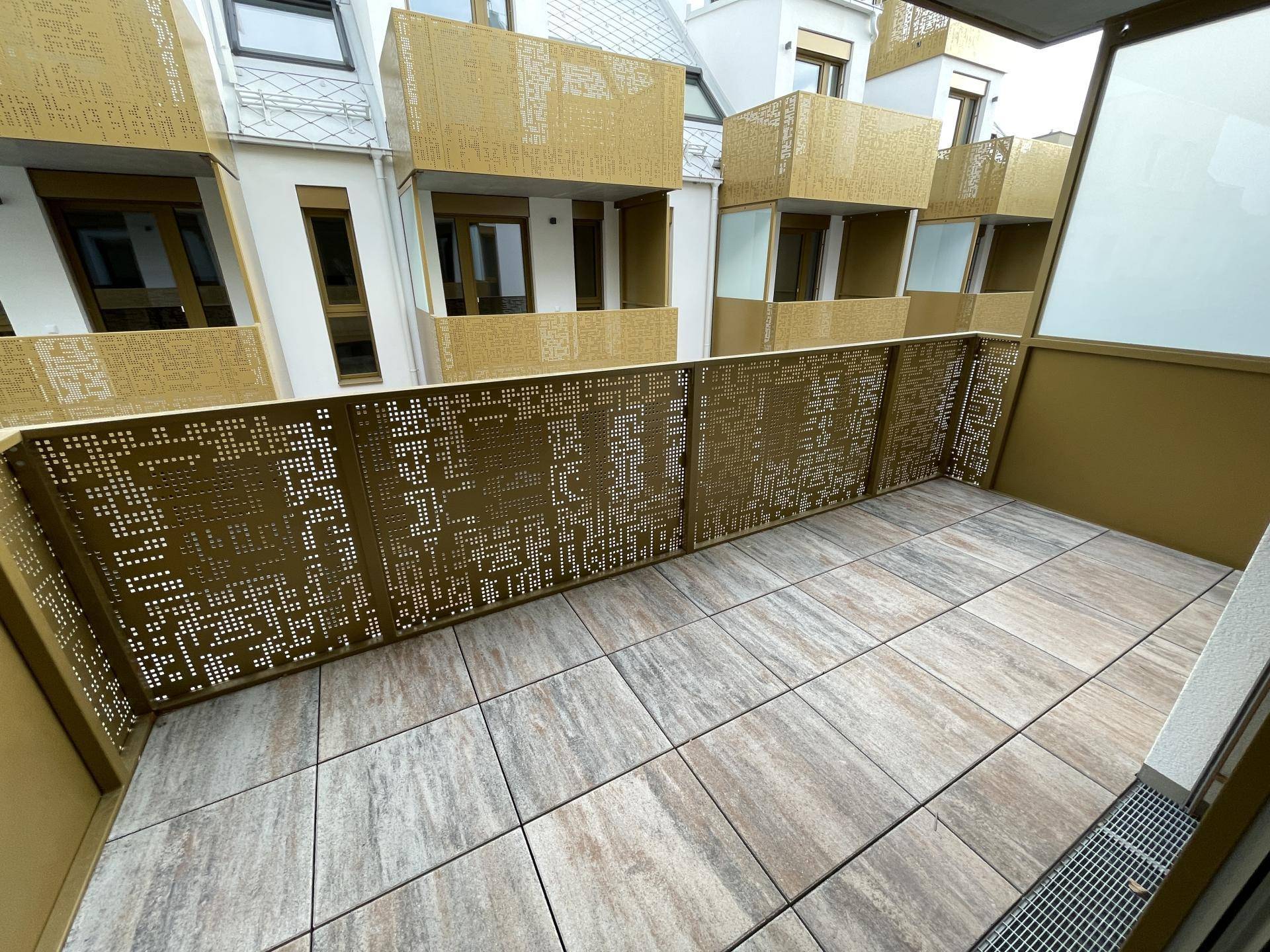 Geräumiger Balkon mit Fliesenboden und modernem, perforiertem Geländer.