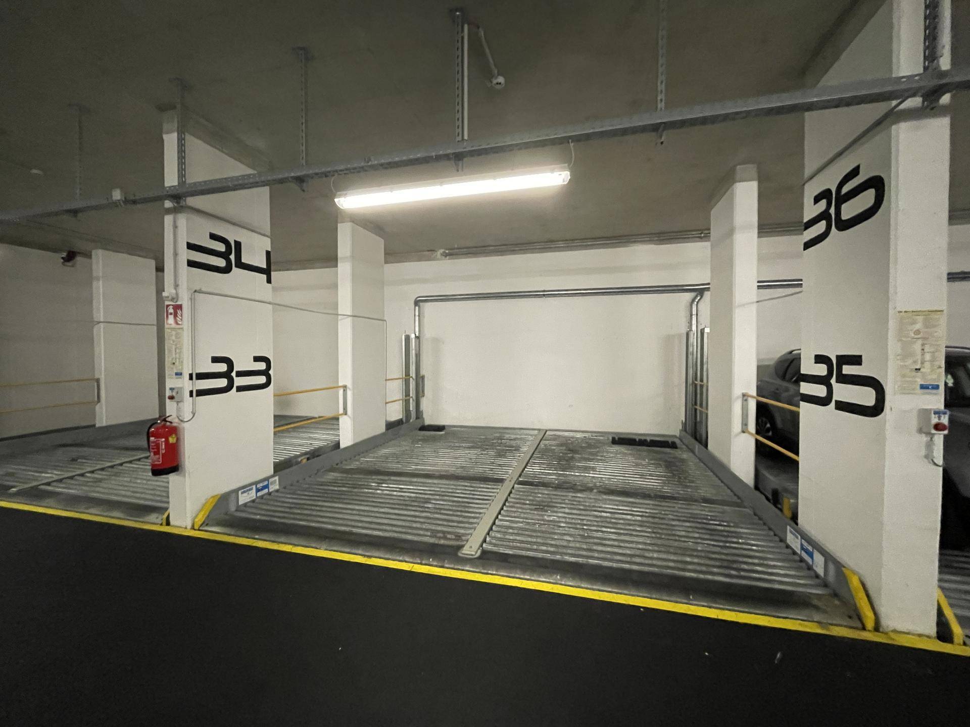Gut beleuchteter Tiefgaragenstellplatz mit automatischem Parksystem und Brandschutz in moderner Umgebung.