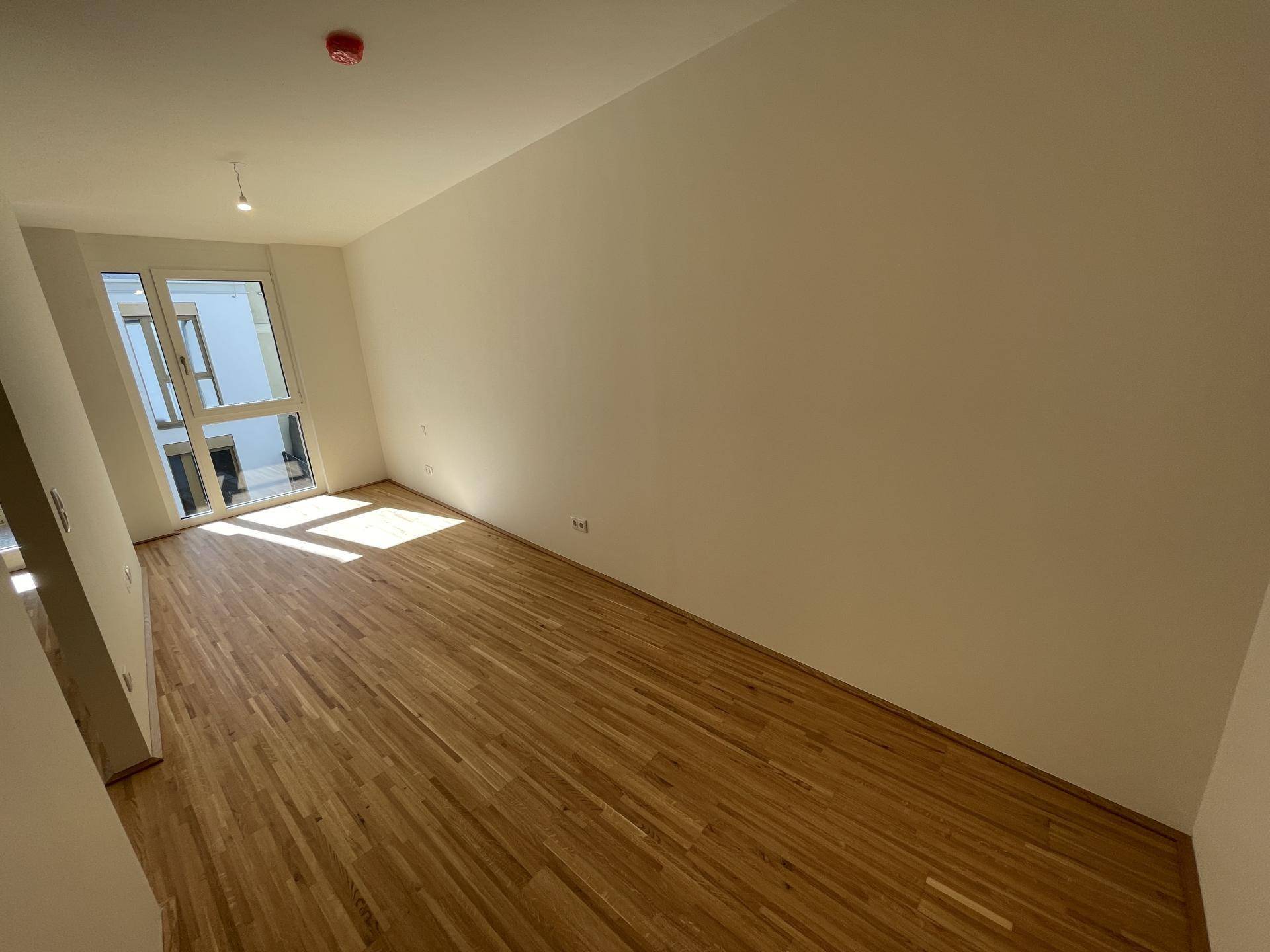 Geräumiges Schlafzimmer mit hellem Parkettboden und großen Fenstern, die viel Licht spenden.