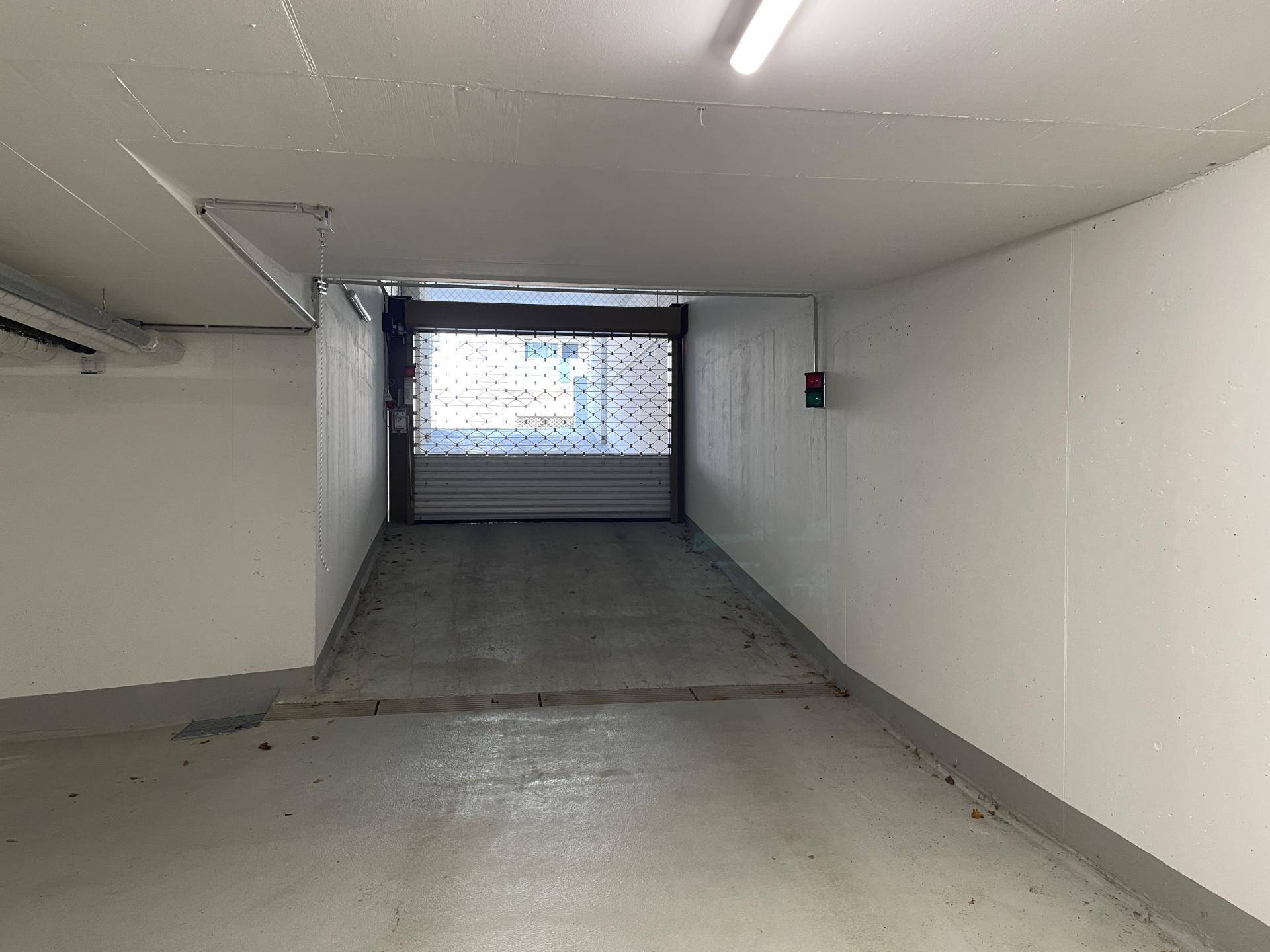 Zufahrt zur Tiefgarage mit geschlossenem Rolltor und hellen Wänden.