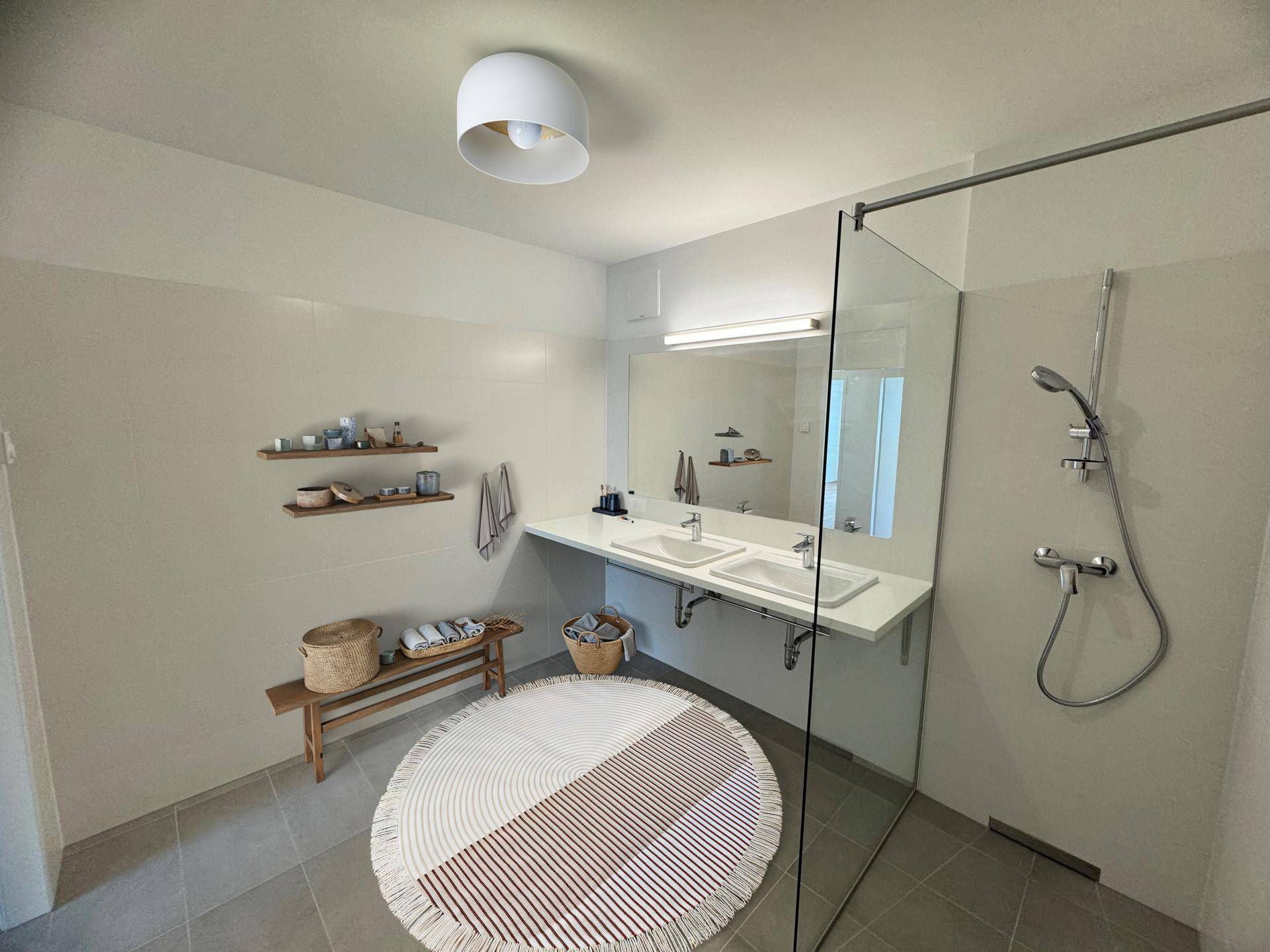 Modernes Badezimmer mit Doppelwaschbecken, großer begehbarer Dusche und hellen Fliesen.