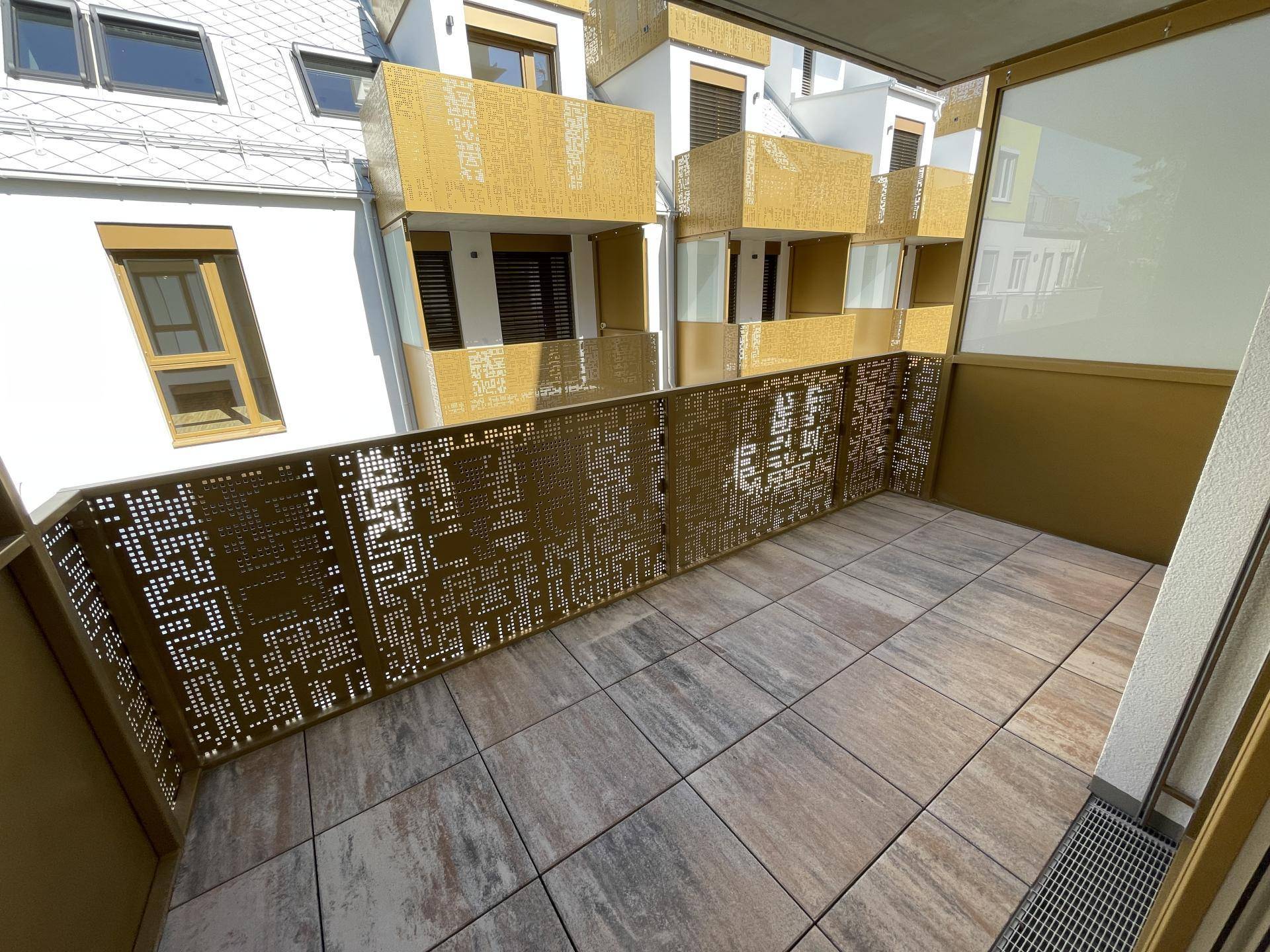 Moderner Balkon mit Fliesenboden und dekorativem Metallgeländer, bietet einen Blick auf die Umgebung.