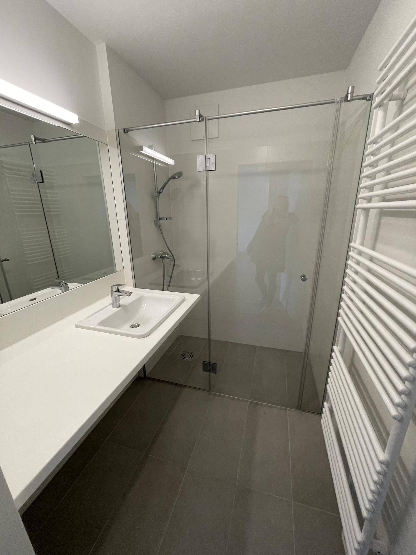 Modernes Badezimmer mit ebenerdiger Dusche, Einzelwaschbecken und beheiztem Handtuchhalter.