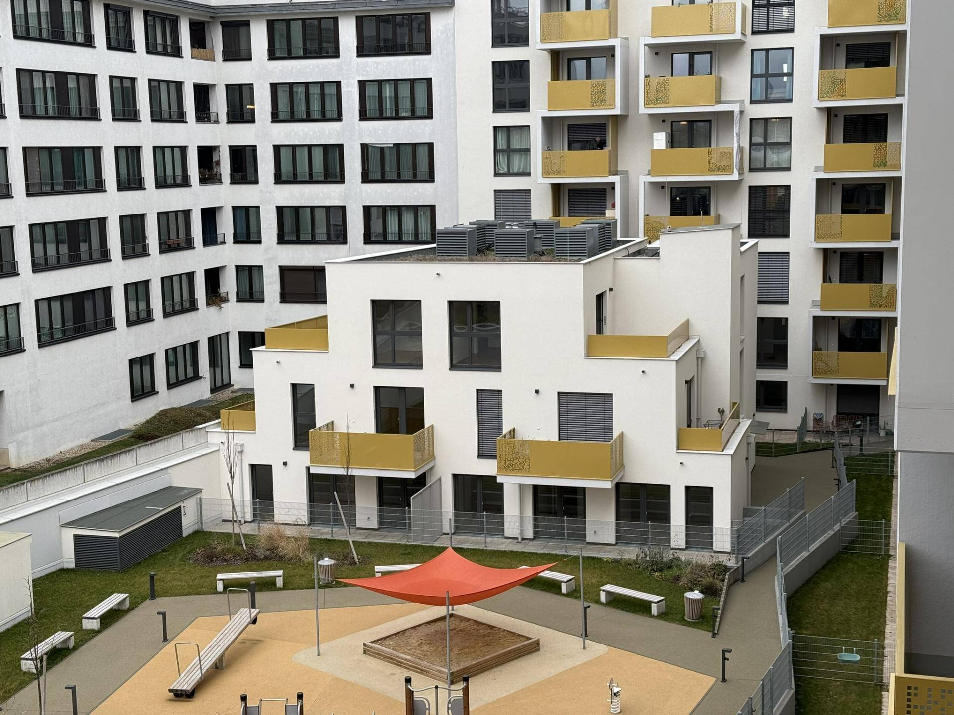 Innenhof der Wohnanlage mit Spielplatz und modernen Gebäuden.