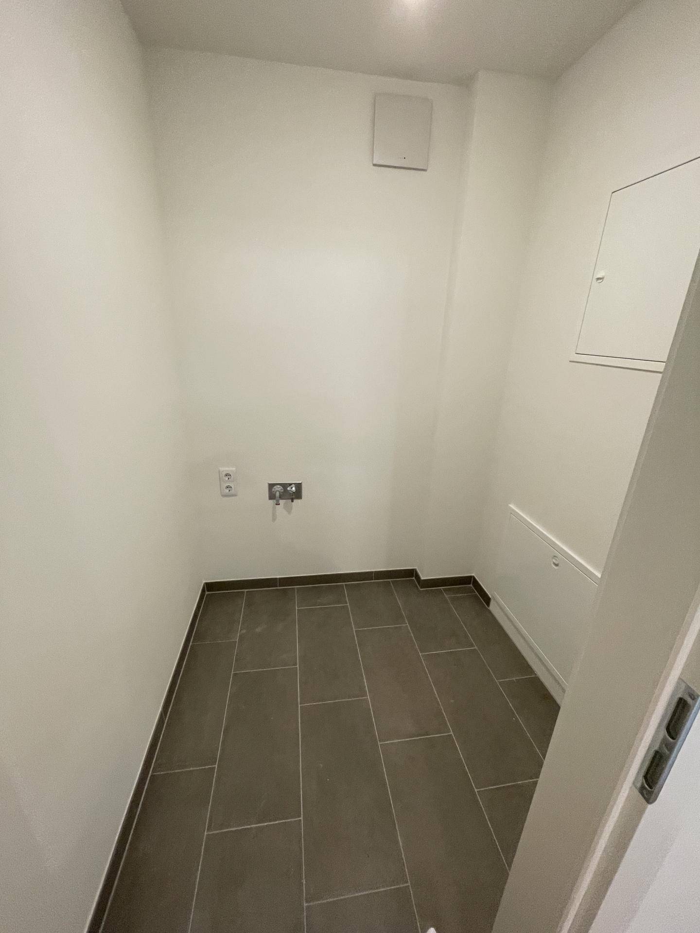 Praktischer Hauswirtschaftsraum mit Fliesenboden und Anschlüssen für Waschmaschine oder Trockner.