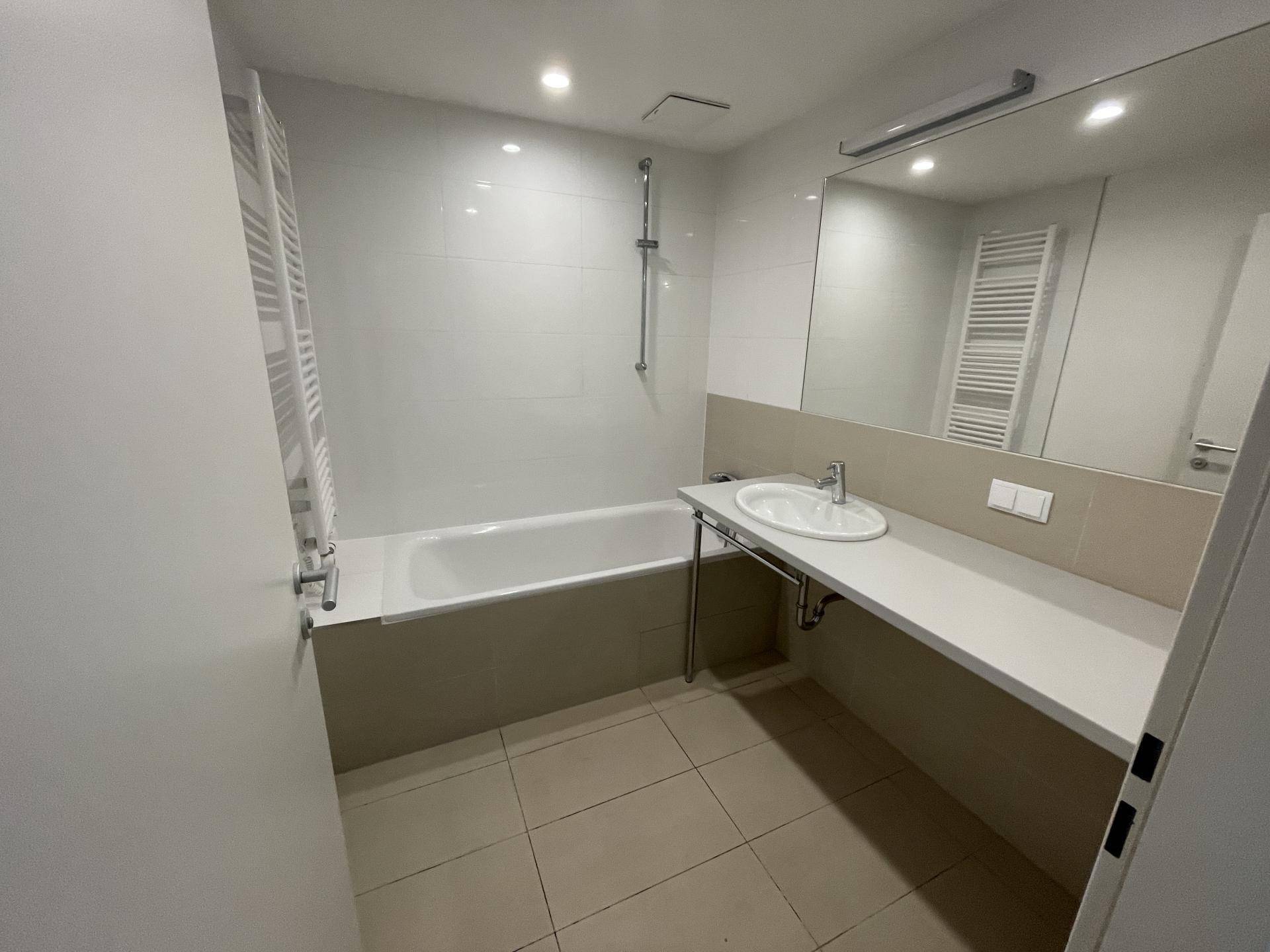 Modernes Badezimmer mit Badewanne, Waschbecken und beheiztem Handtuchhalter.