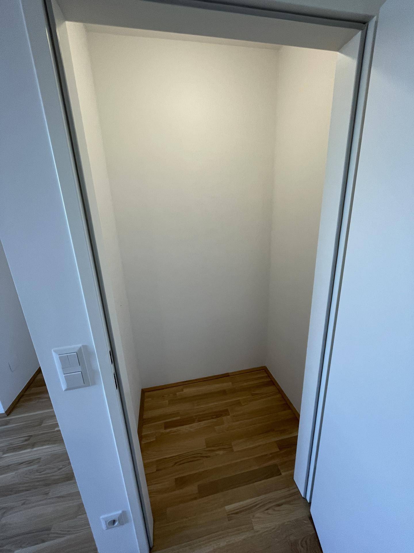 Praktischer Abstellraum mit hellem Holzfußboden und weißen Wänden, ideal für zusätzlichen Stauraum.