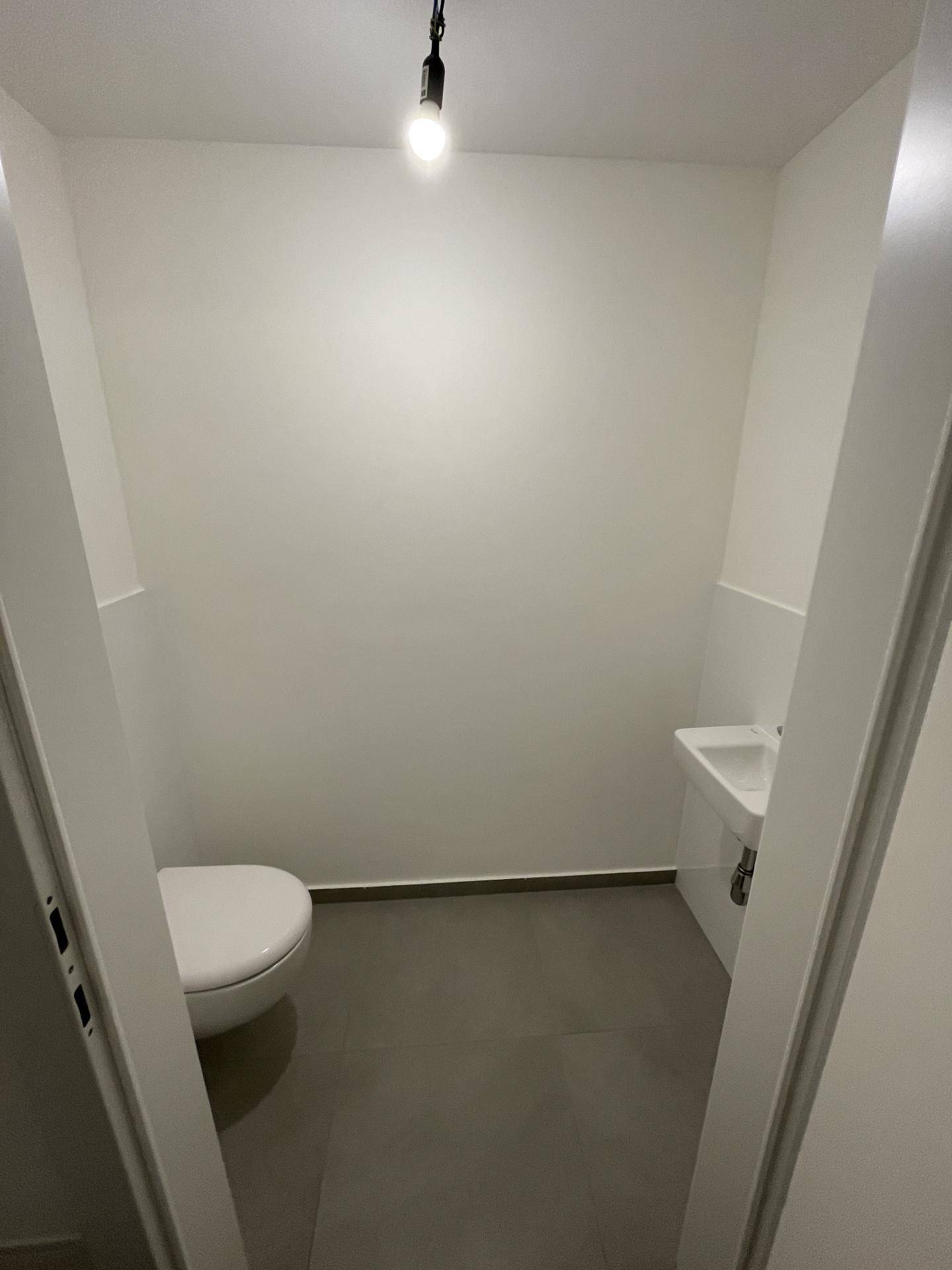 Kleines, separates WC mit wandhängender Toilette und Handwaschbecken, in schlichtem Design.