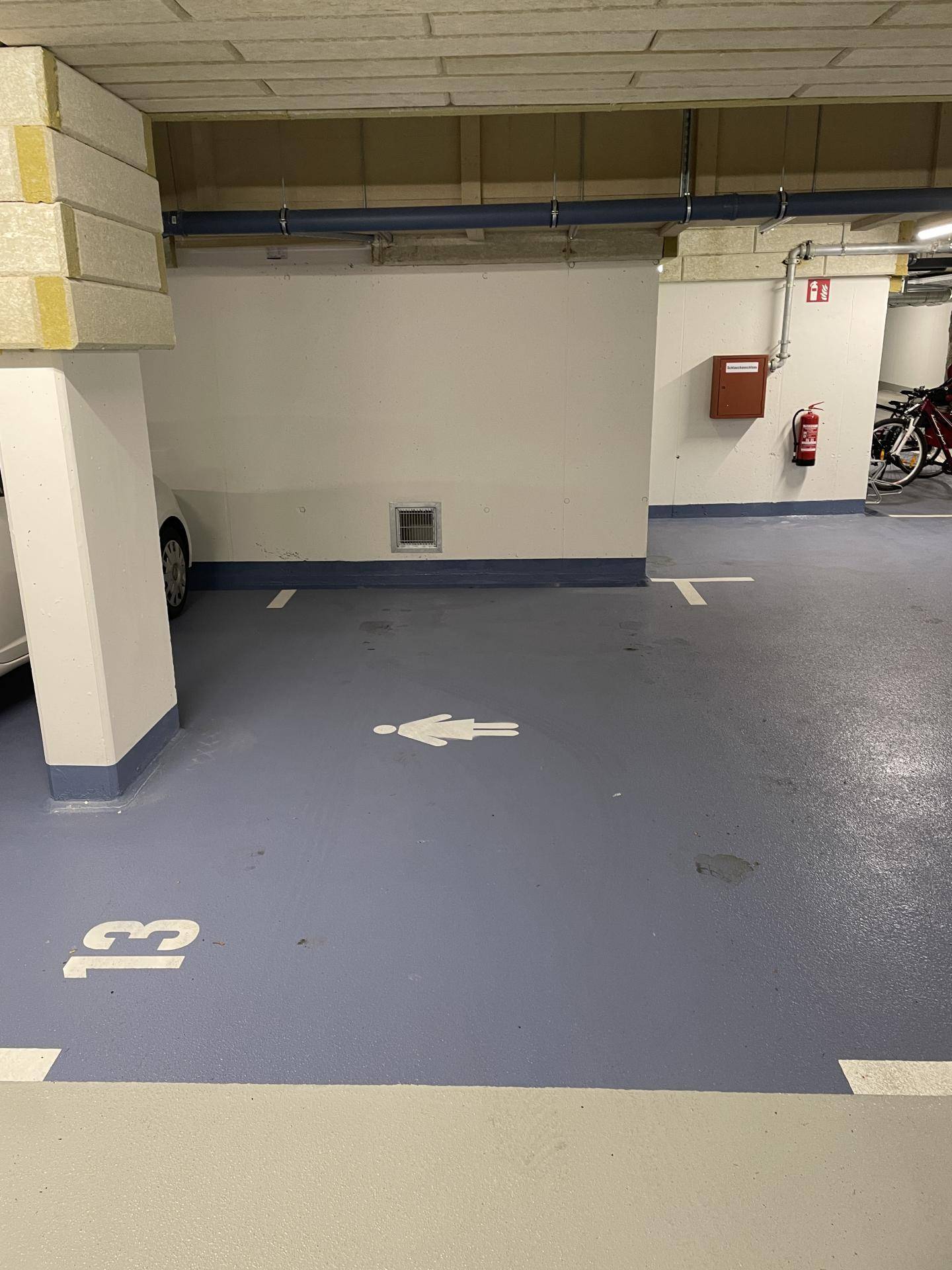 Tiefgaragenstellplatz G3 mit Markierung und Feuerlöscher in einem modernen Gebäude.