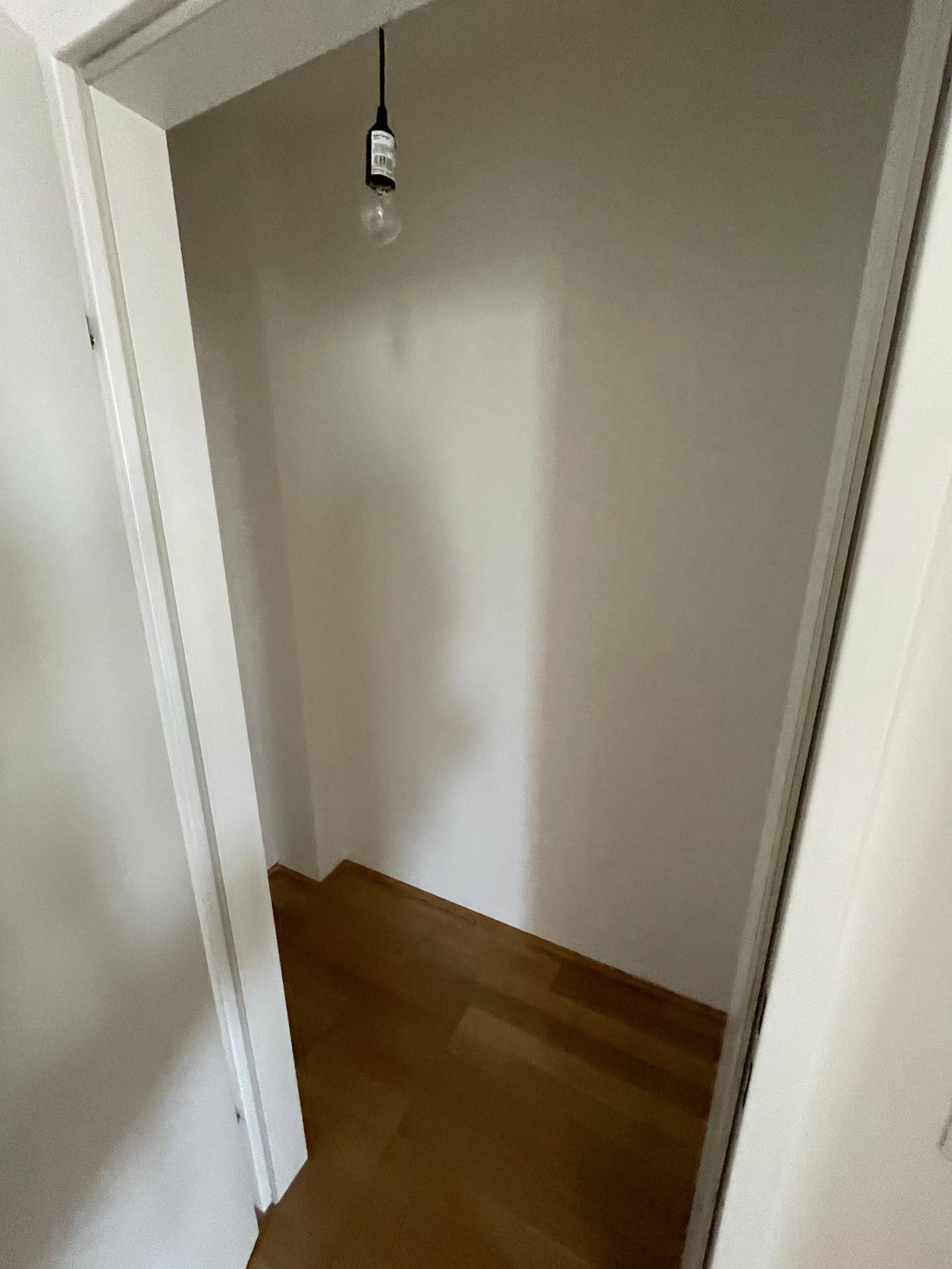 Kleiner Abstellraum mit Parkettboden und einfacher Beleuchtung.