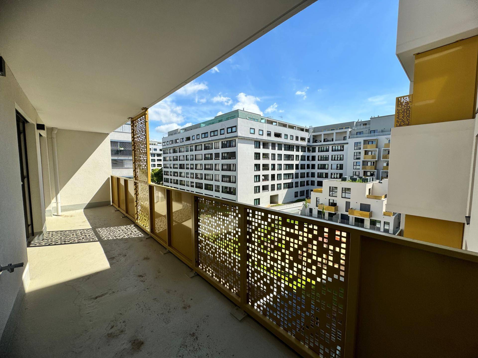 Langer Balkon mit moderner Metallbrüstung und Blick auf die Wohnanlage.