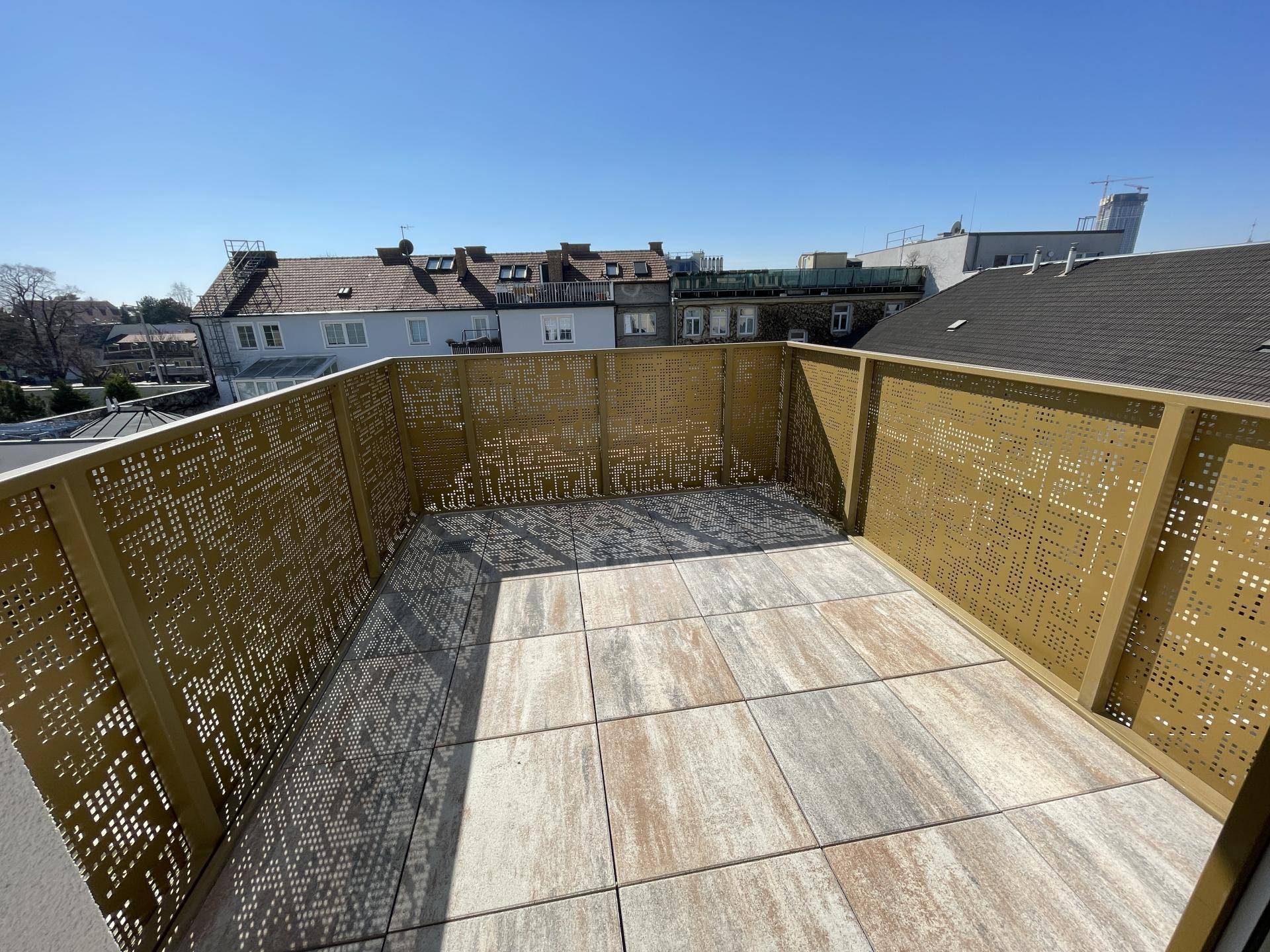 Große Dachterrasse mit Fliesenboden und perforierter Metallbrüstung, bietet einen weiten Blick.