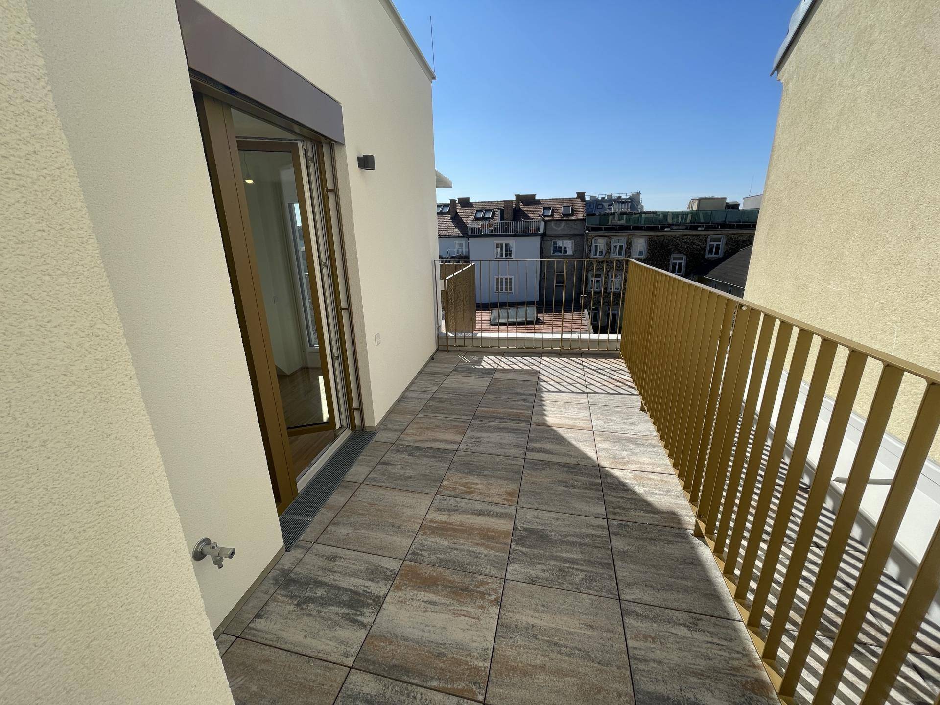 Sonniger Balkon mit Fliesenboden und goldener Brüstung, ideal für entspannte Stunden im Freien.