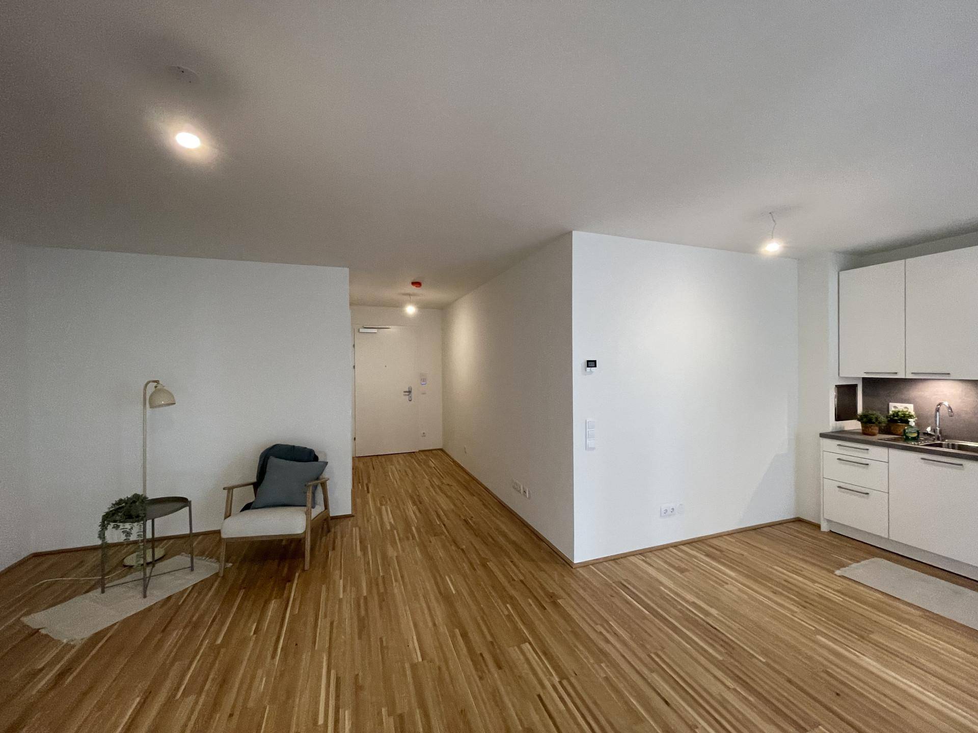 Offener Grundriss verbindet Eingangsbereich, Küche und Wohnzimmer mit durchgehendem Holzboden.