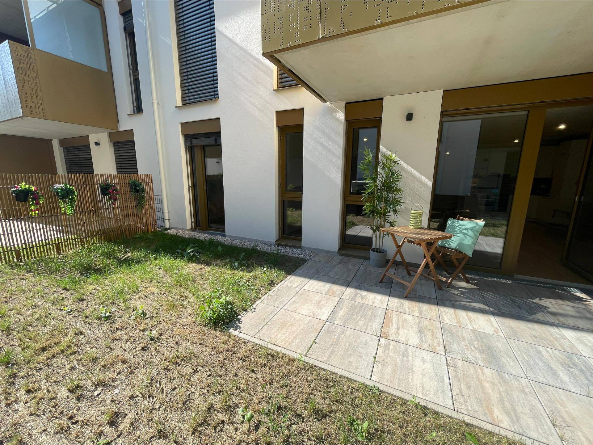 Gemütliche Terrasse mit Sitzgelegenheiten und angrenzender Rasenfläche im Freien.