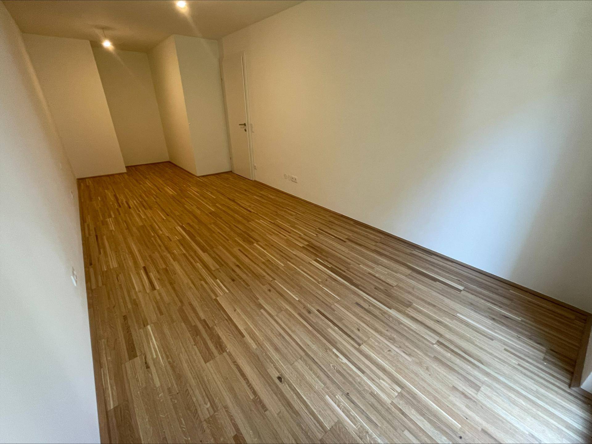 Geräumiges Zimmer mit Parkettboden und weißen Wänden, bereit zur individuellen Gestaltung.