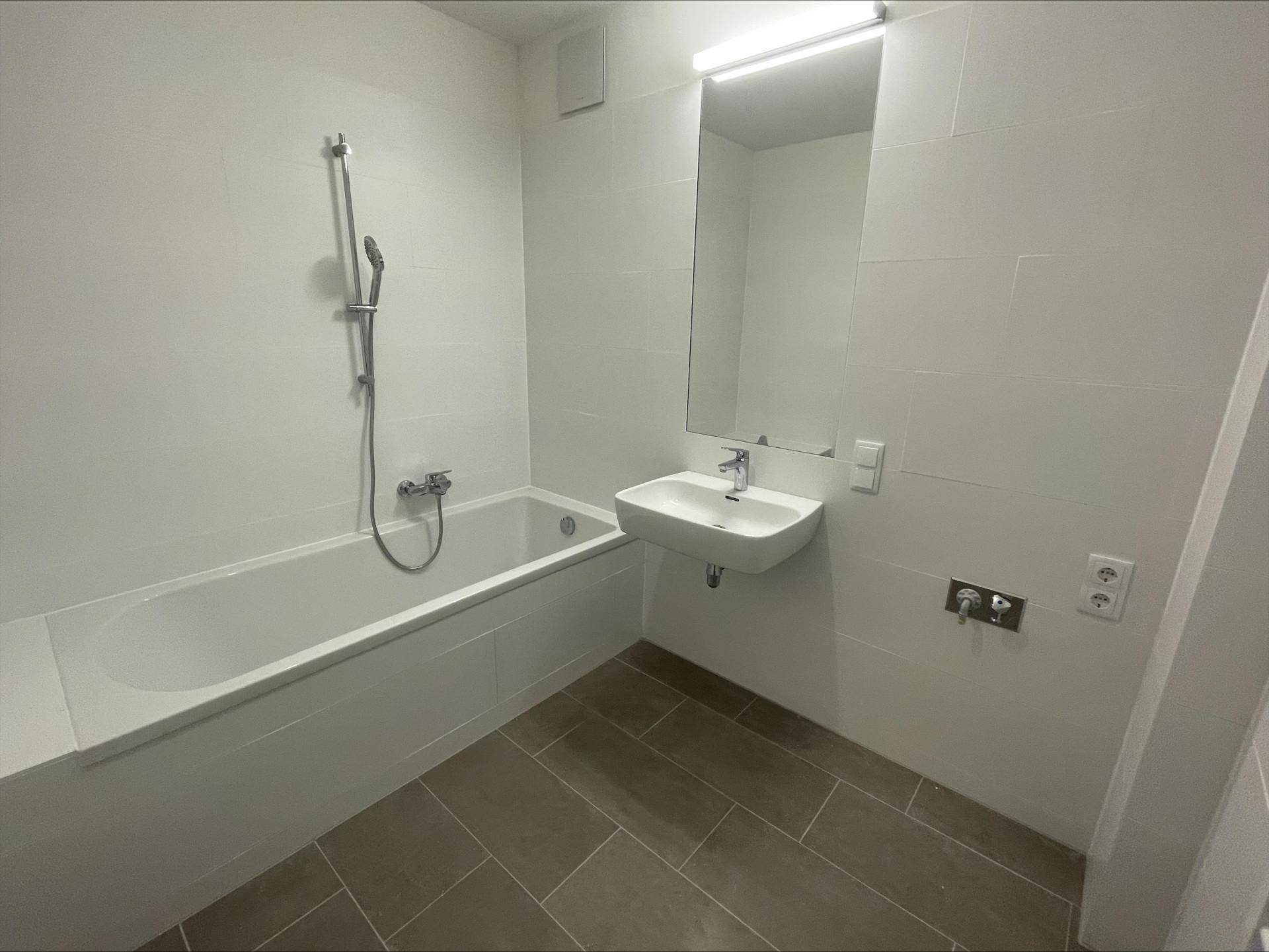 Modernes Badezimmer mit Badewanne, Waschbecken und weißen Wand- und Bodenfliesen.