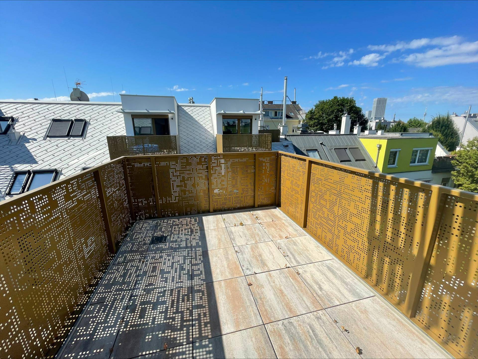 Geräumige Dachterrasse mit modernen Metallgeländern und Blick über die umliegenden Dächer der Stadt.
