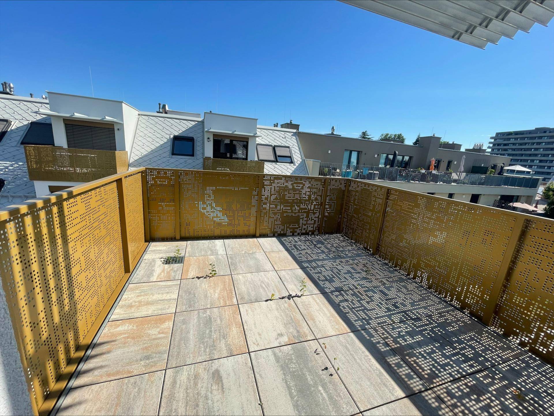 Weitläufige Dachterrasse mit modernen Fliesen und perforierten Metallgeländern, bietet einen Panoramablick.