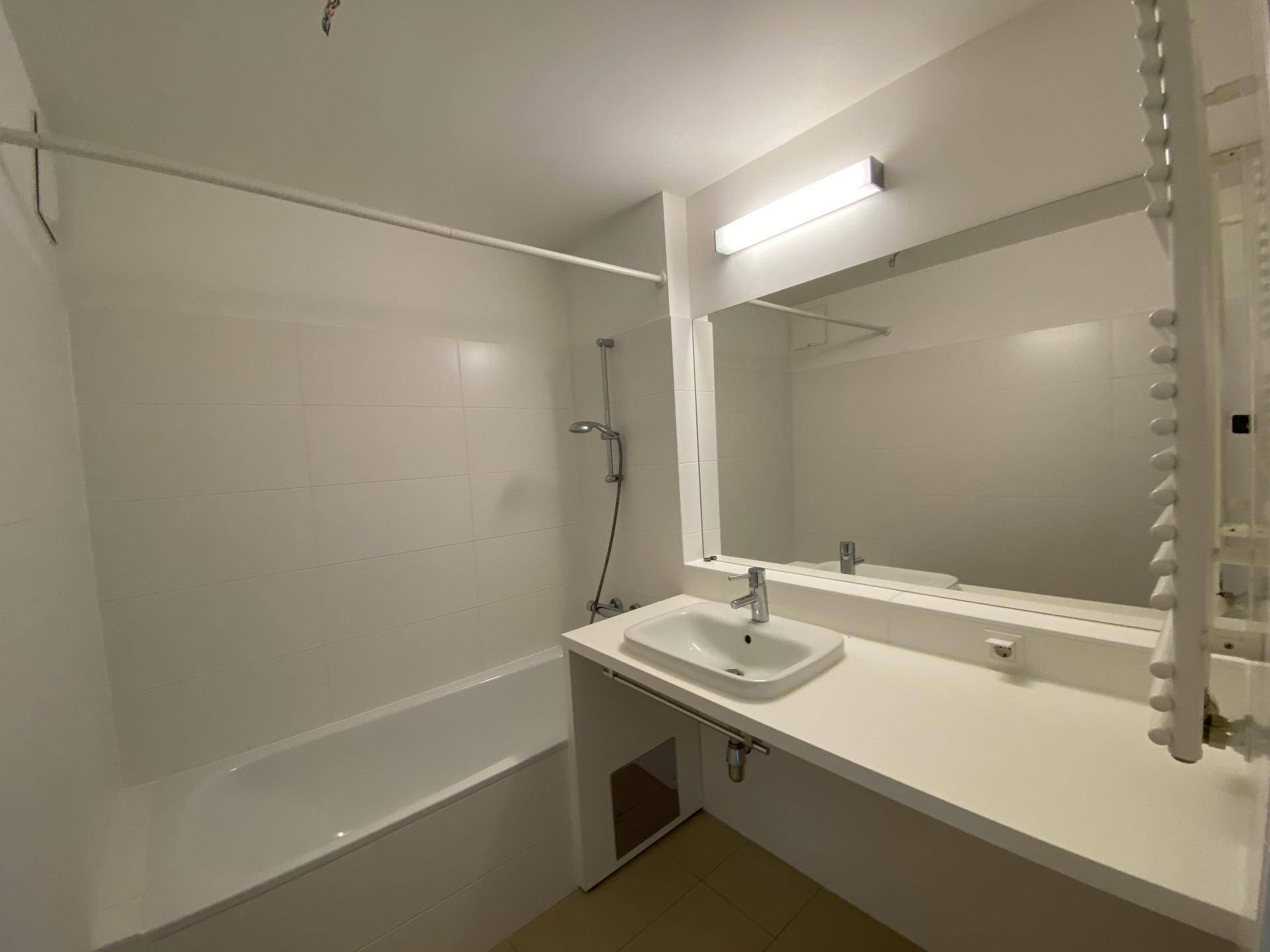 Modernes Badezimmer mit Badewanne, Einzelwaschbecken und beheiztem Handtuchhalter.