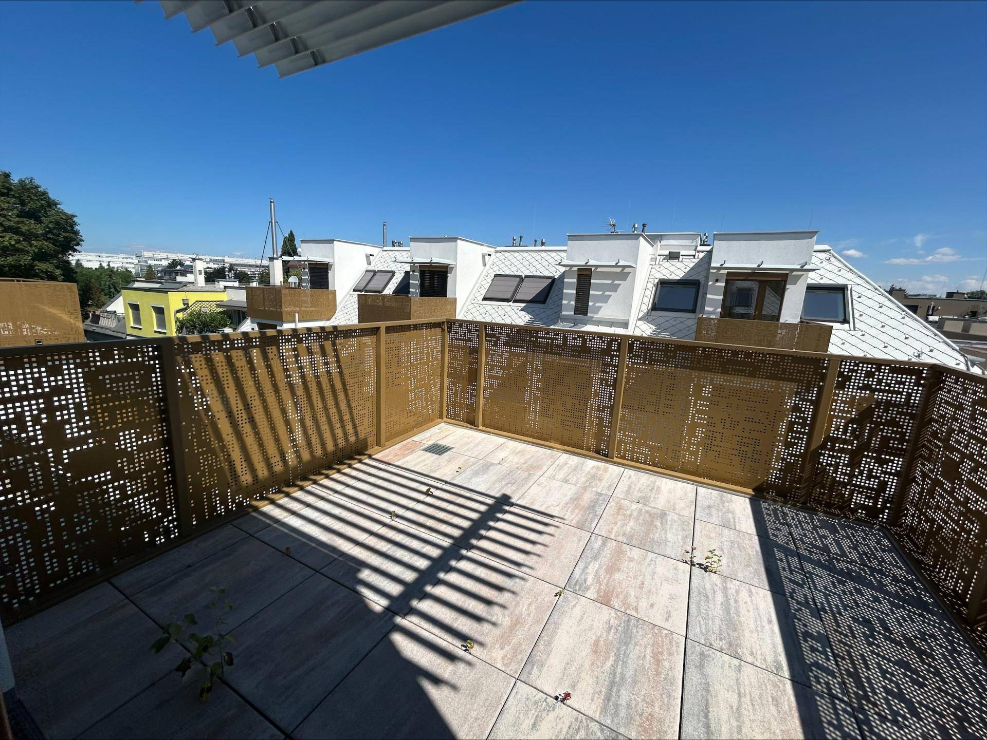 Sonnige Dachterrasse mit modernen Metallgeländern und weitem Blick über die Dächer der Stadt.