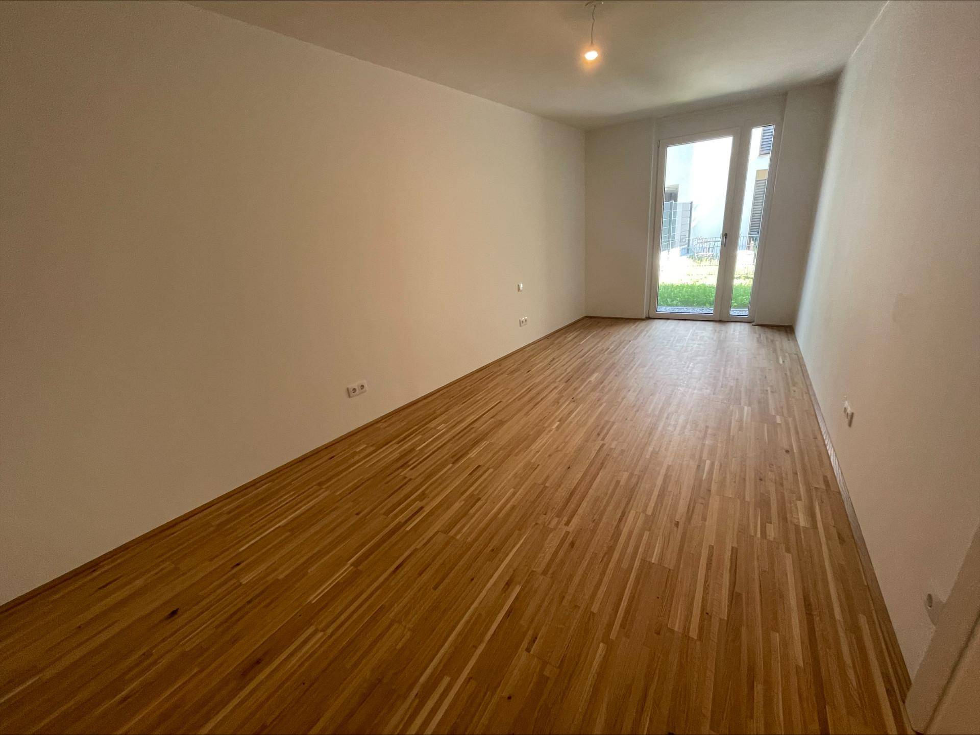 Helles Schlafzimmer mit Parkettboden und direktem Zugang zum Außenbereich.