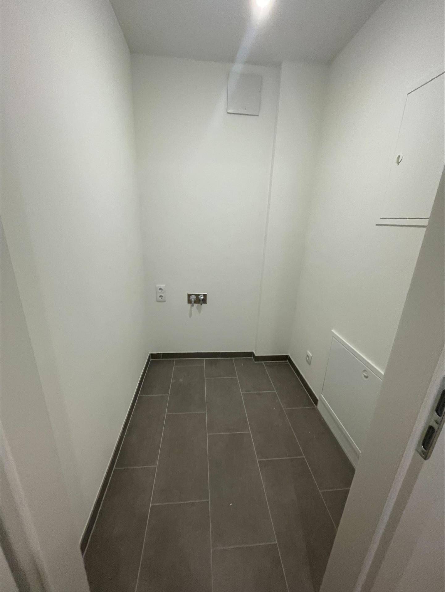 Praktischer Abstellraum mit Fliesenboden und Anschlüssen für Haushaltsgeräte.