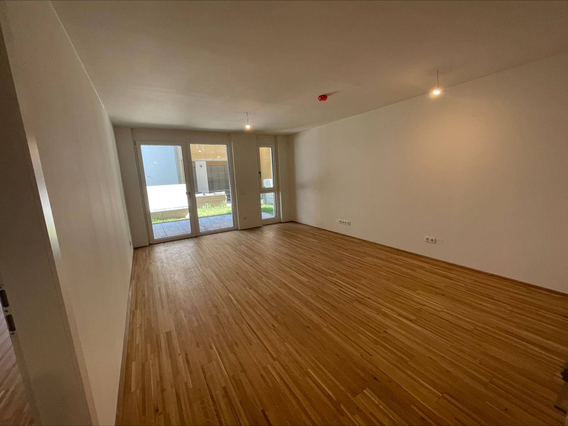 Geräumiger Wohnbereich mit Holzboden und Zugang zu einer Außenterrasse.